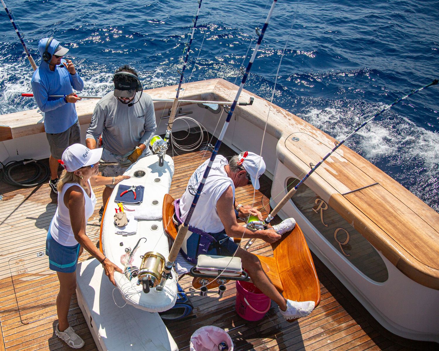 Aerial view of a fishing boat crew preparing tackle and fishing rods on a sunny deep sea sport fishing charter.