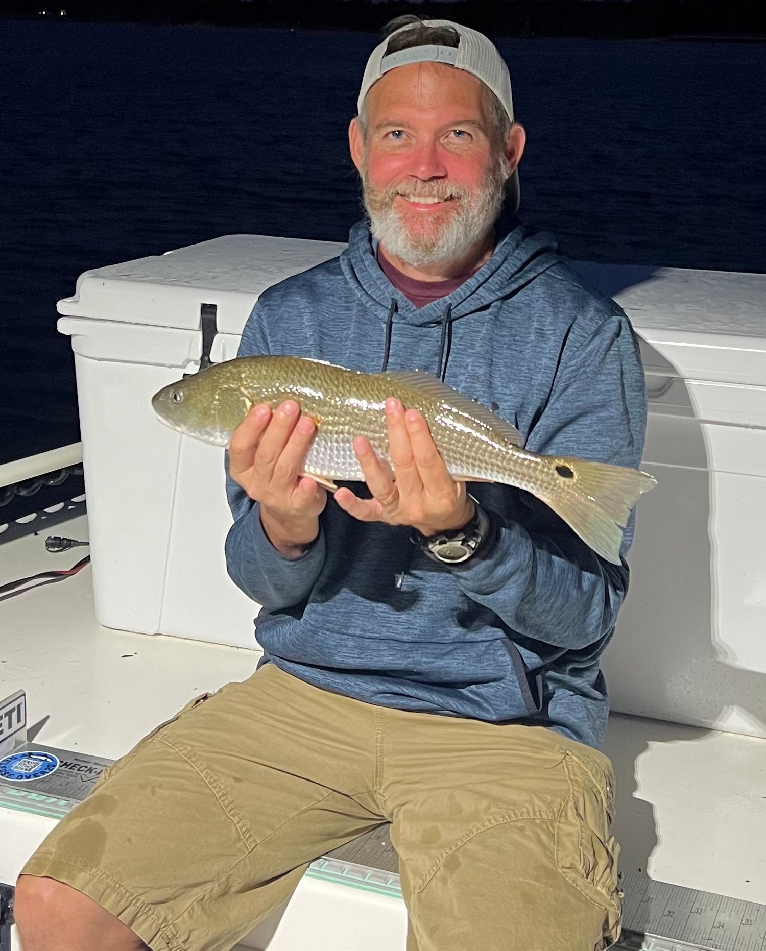 Evening redfish catch displayed on boat with cooler and night sky backdrop.