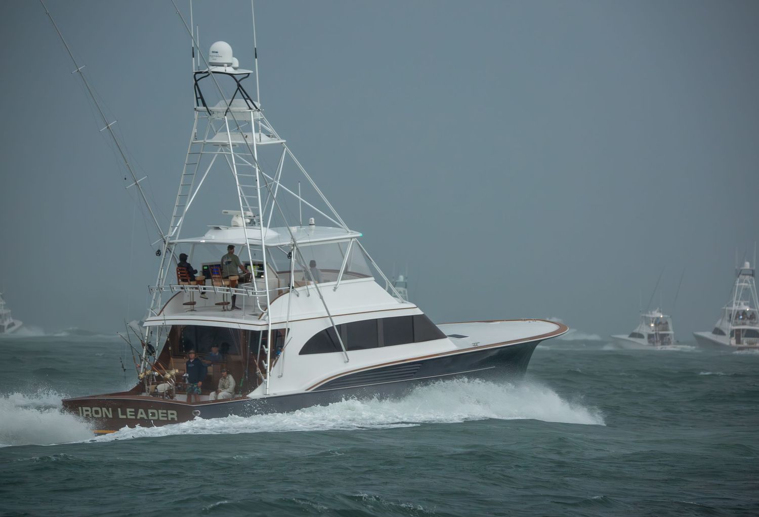 Sport fishing boats navigate through rough ocean waters during stormy conditions.