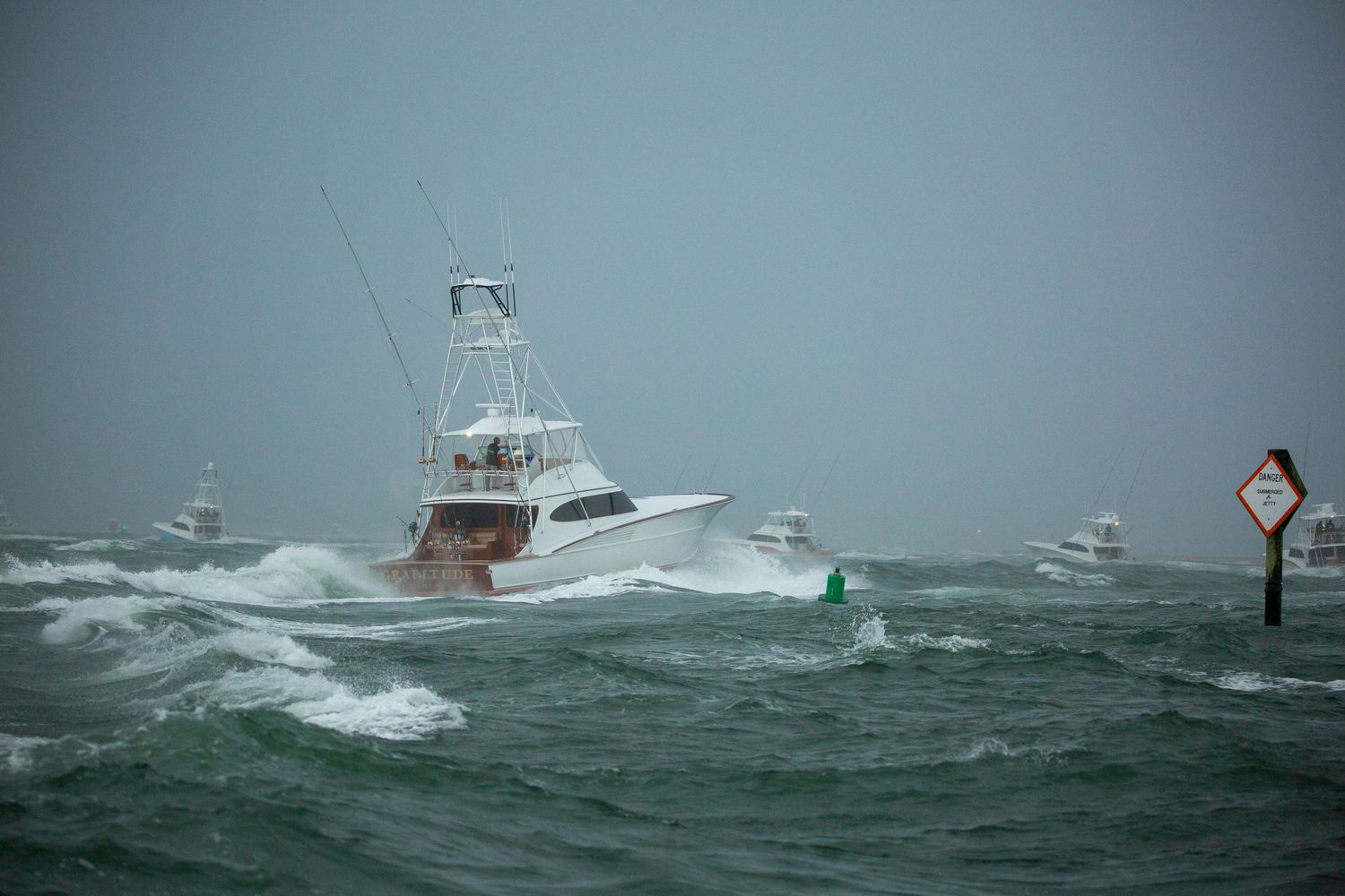 Sport fishing vessel struggles against large waves in stormy weather.