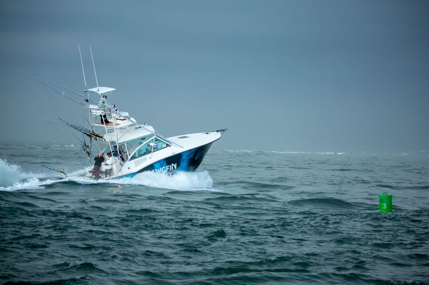 Fishing charter boat navigates through turbulent ocean waves near shoreline.