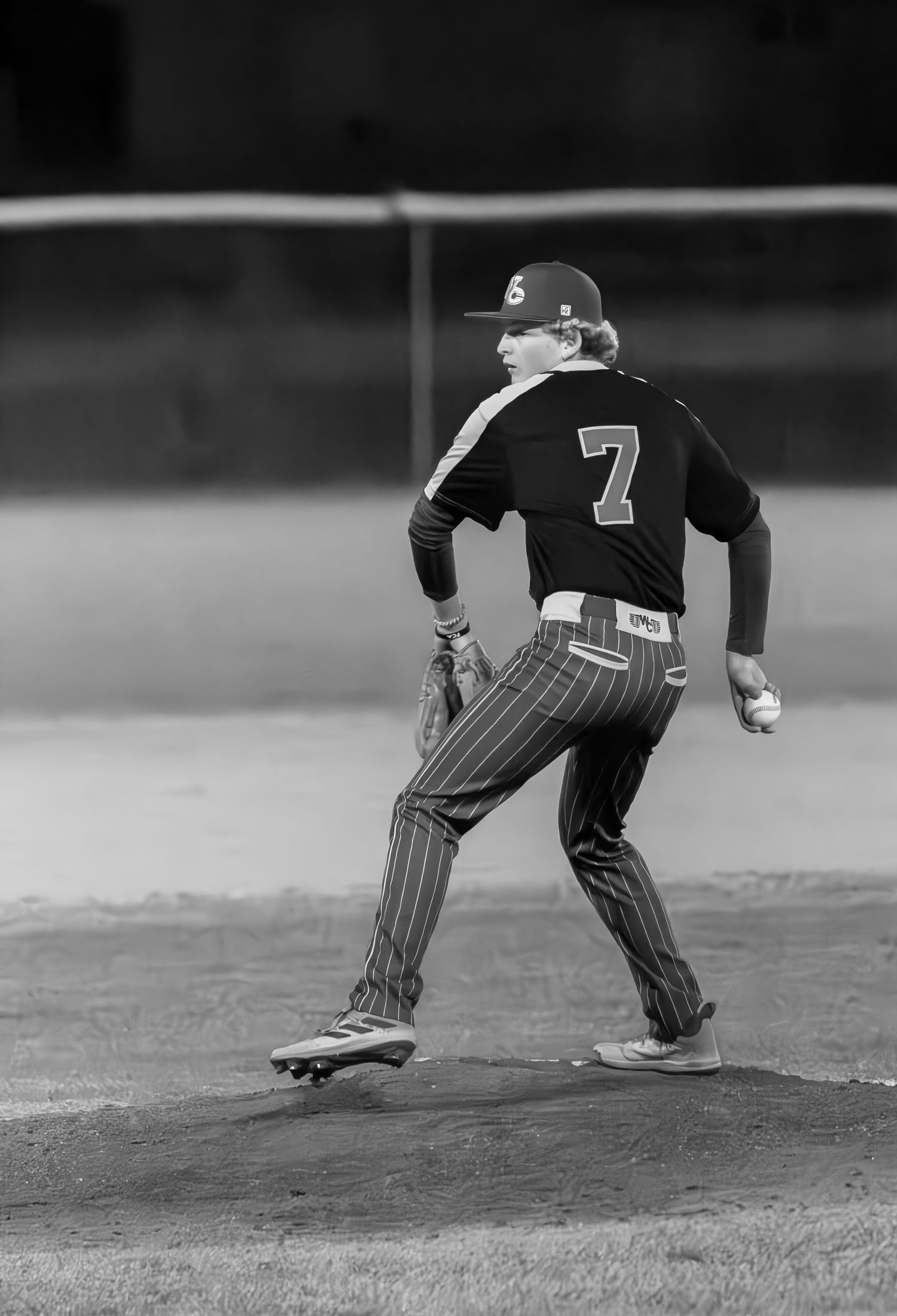 Baseball player demonstrating follow-through pitching technique on field in vintage style photograph.