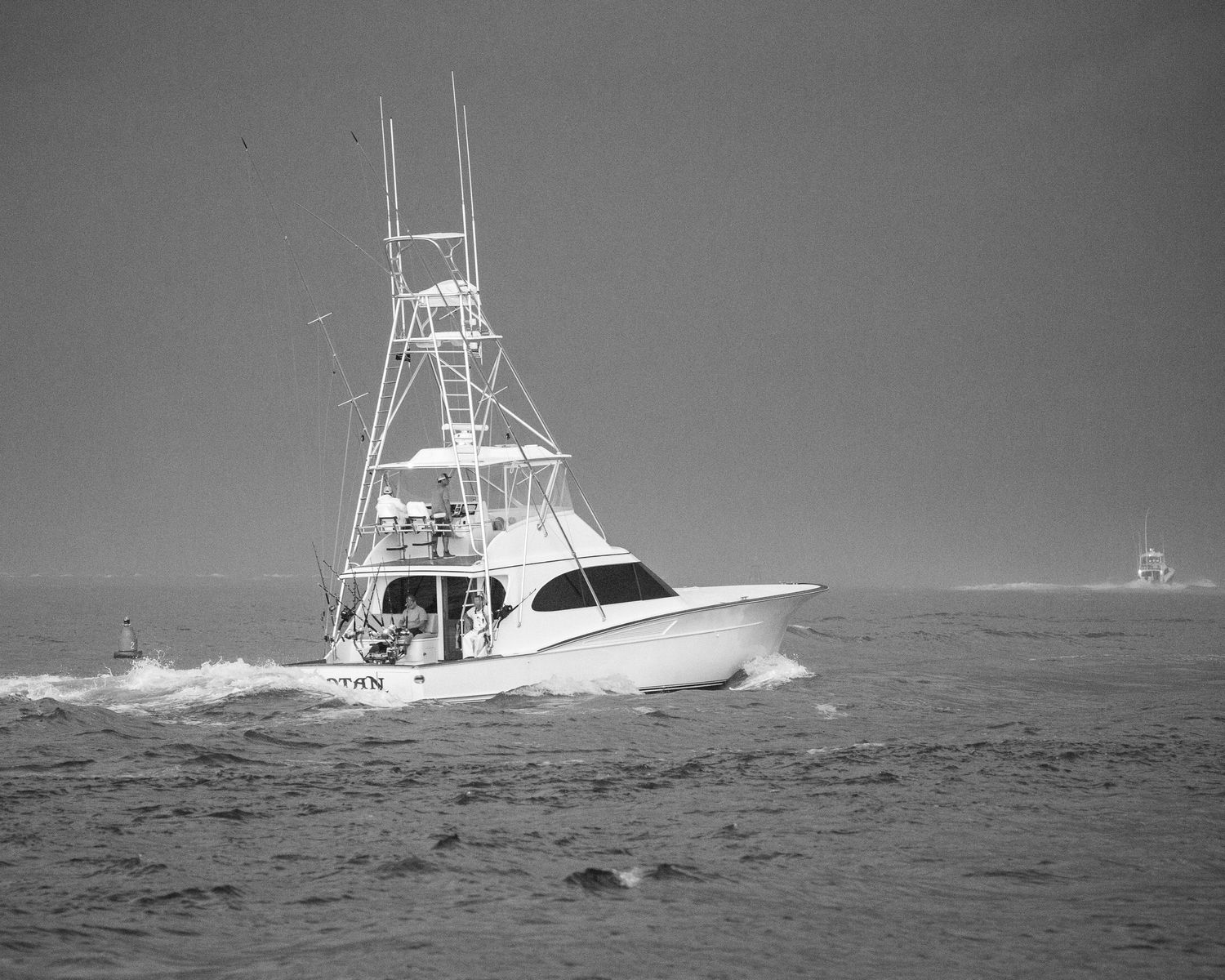 White sportfishing yacht navigating through rough ocean waves.