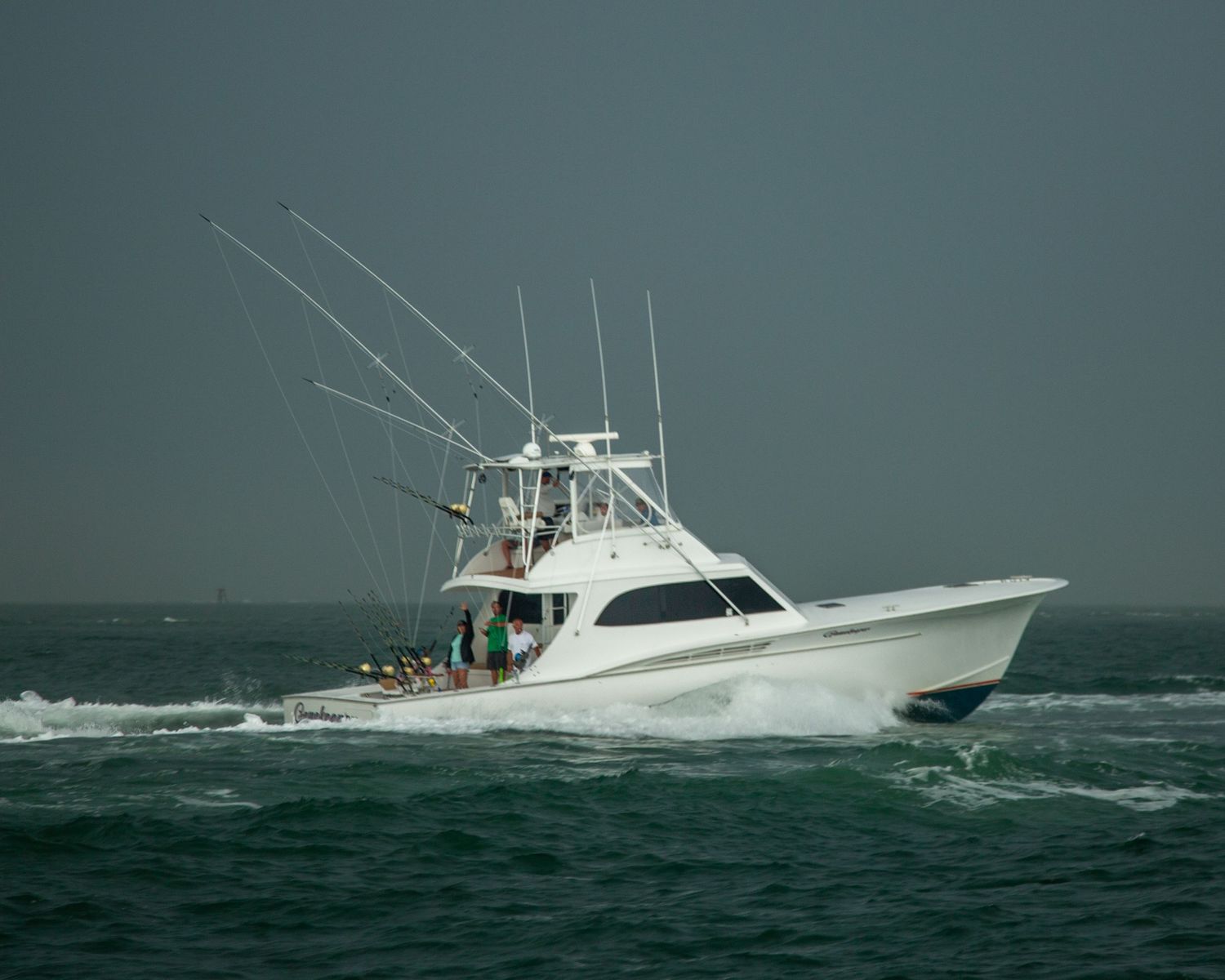 Sport fishing boat cuts through stormy seas against moody teal-colored sky.