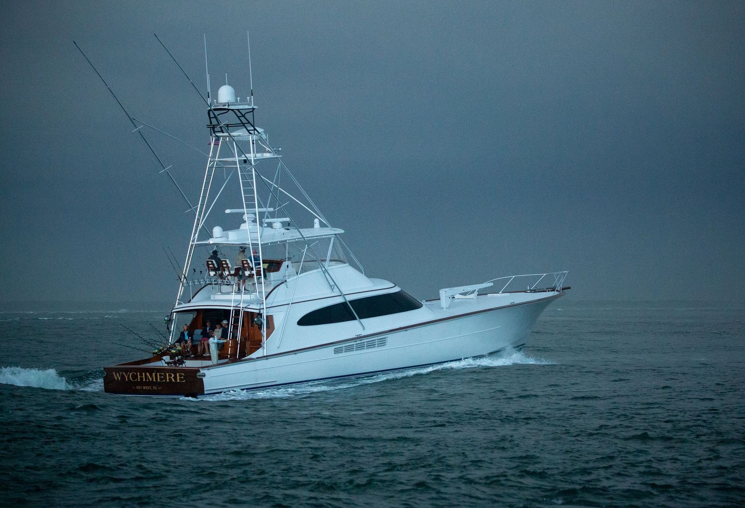 White sport fishing yacht cutting through stormy waters in gloomy weather conditions.