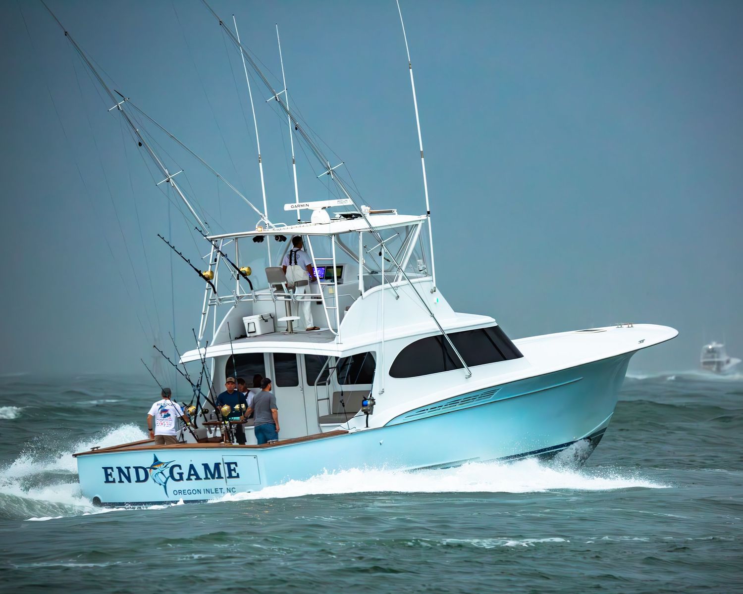 Sport fishing vessel named End Game powers through rough seas with multiple fishing rods mounted.