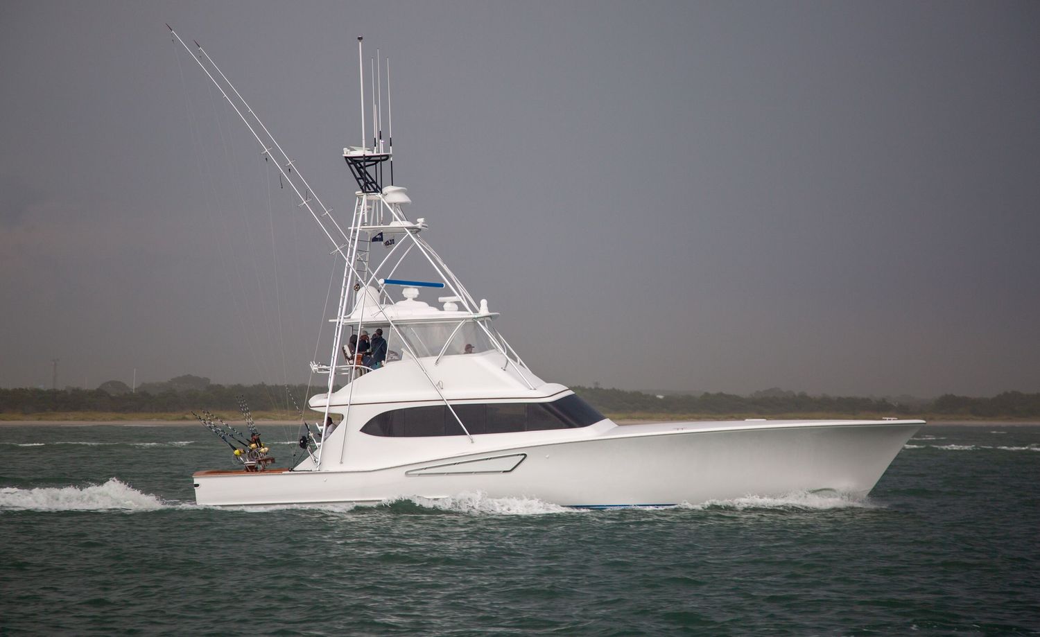 White sport fishing vessel navigating through choppy waters at high speed.