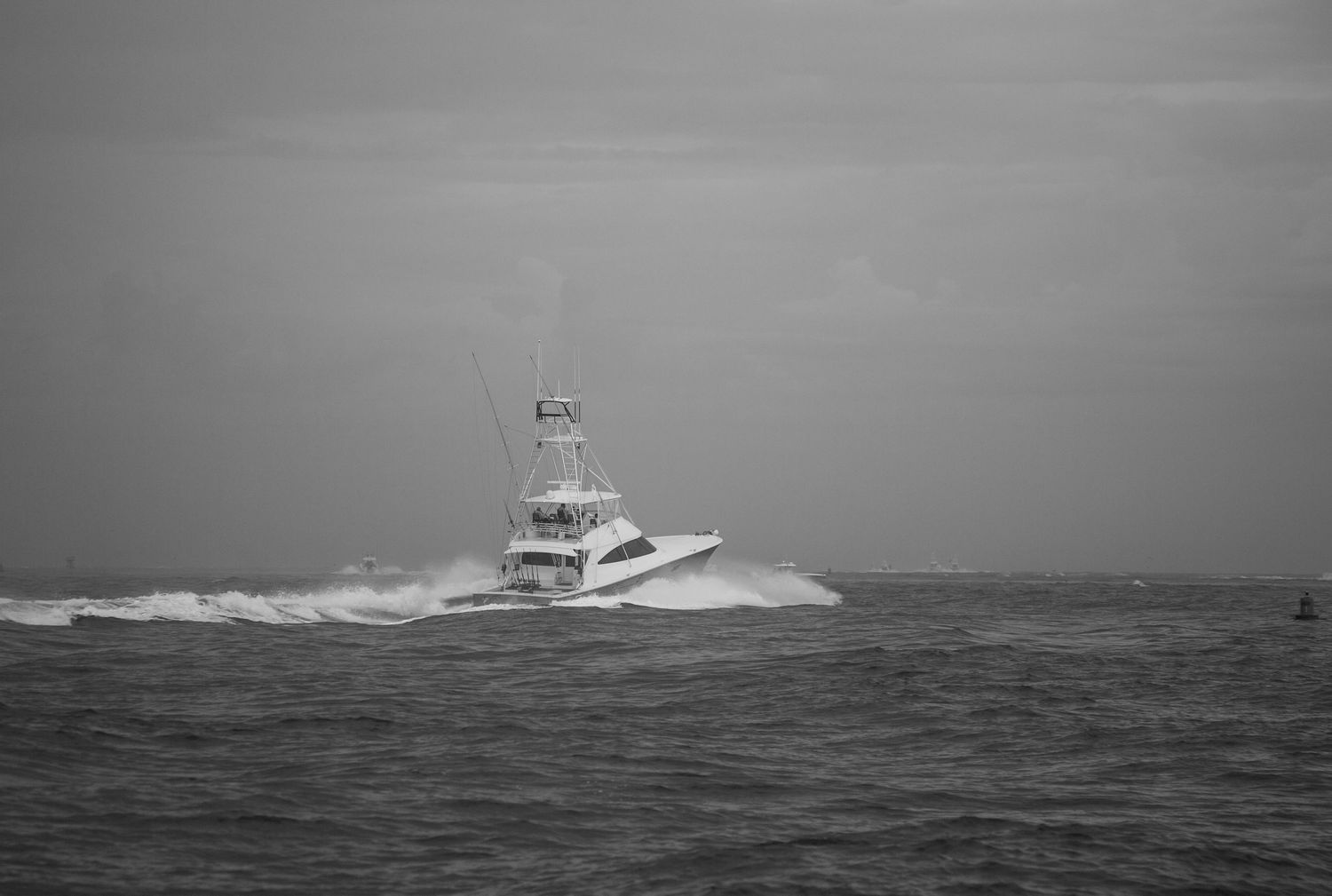 Large yacht powers through turbulent ocean waves in monochrome.