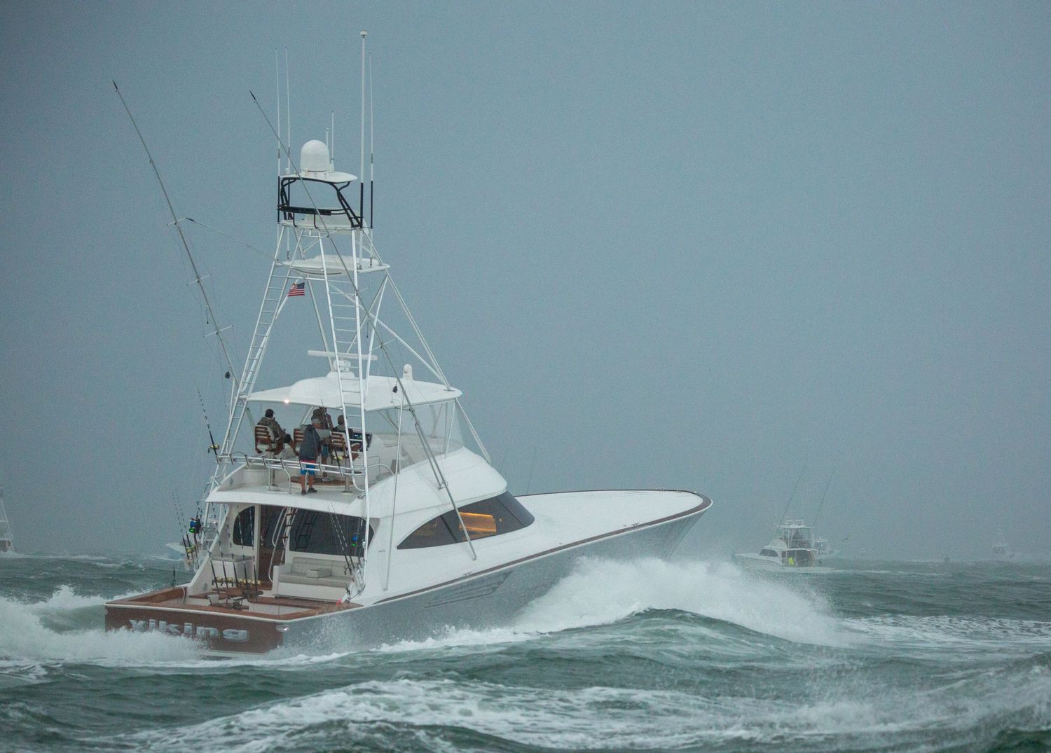 Recreational fishing boats navigate rough waters near coastal markers during stormy conditions.