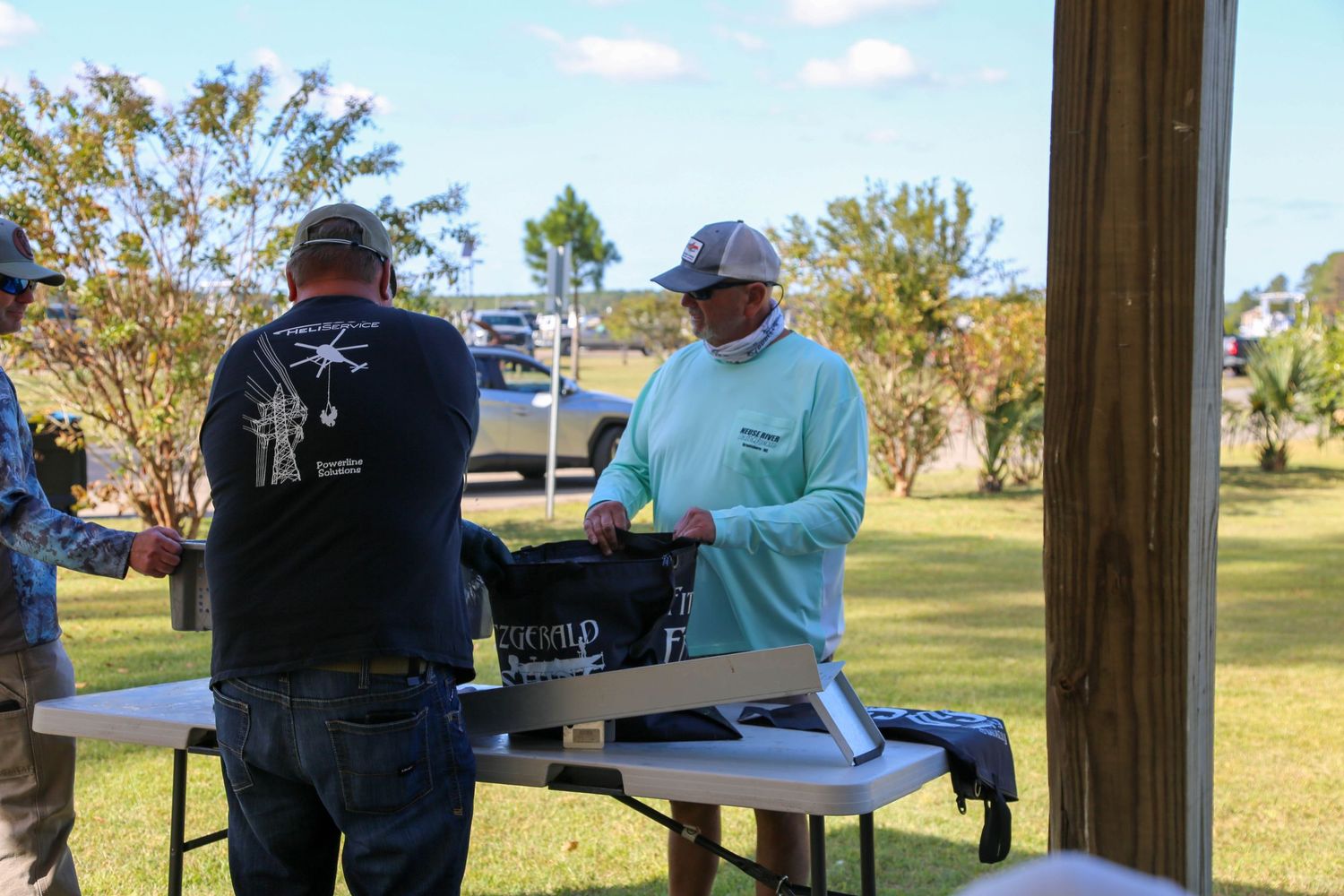 Officials weighing and recording fish catches at outdoor tournament station.