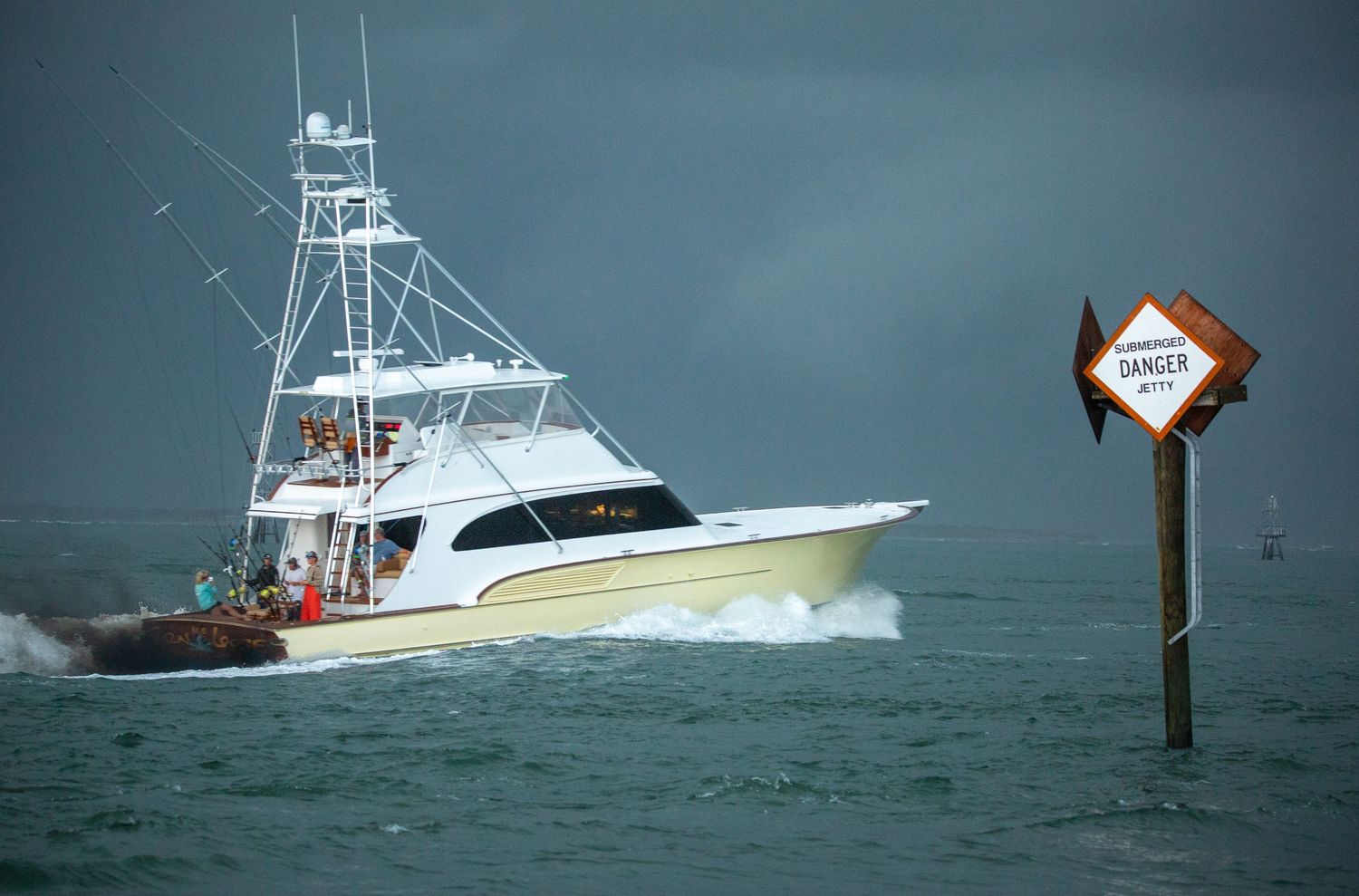 Fishing vessels navigate past channel markers in rough ocean conditions with dark storm clouds overhead.