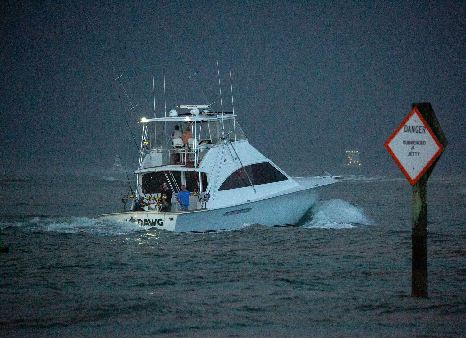 Sport fishing boat navigating past a warning marker in stormy conditions.