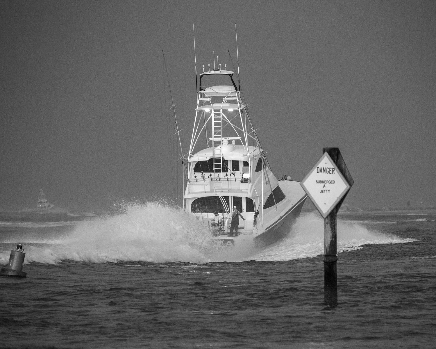 Sport fishing boats navigate through rough ocean waters near channel markers during stormy conditions.