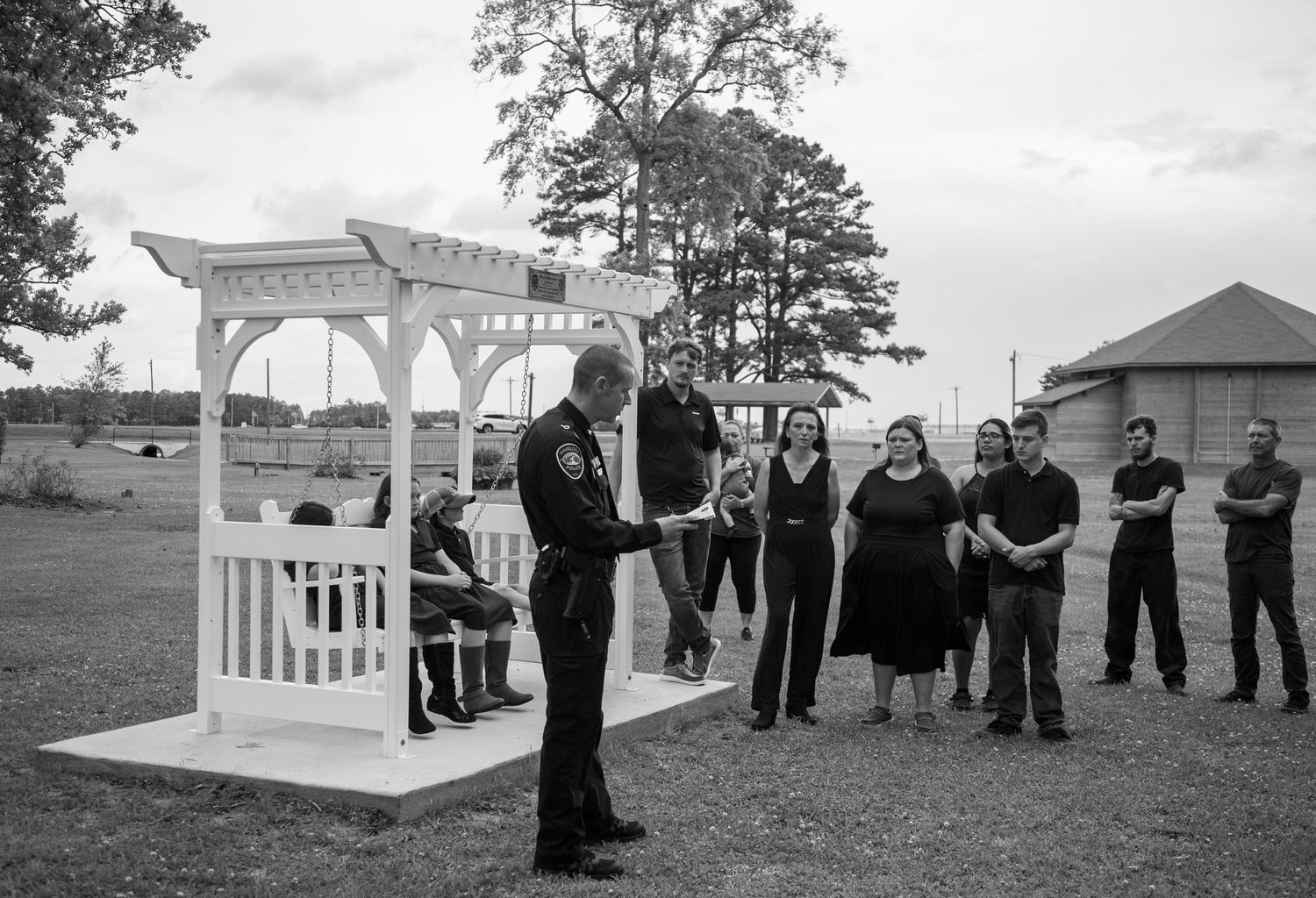 Black and white photo of group gathered around gazebo during outdoor ceremony.