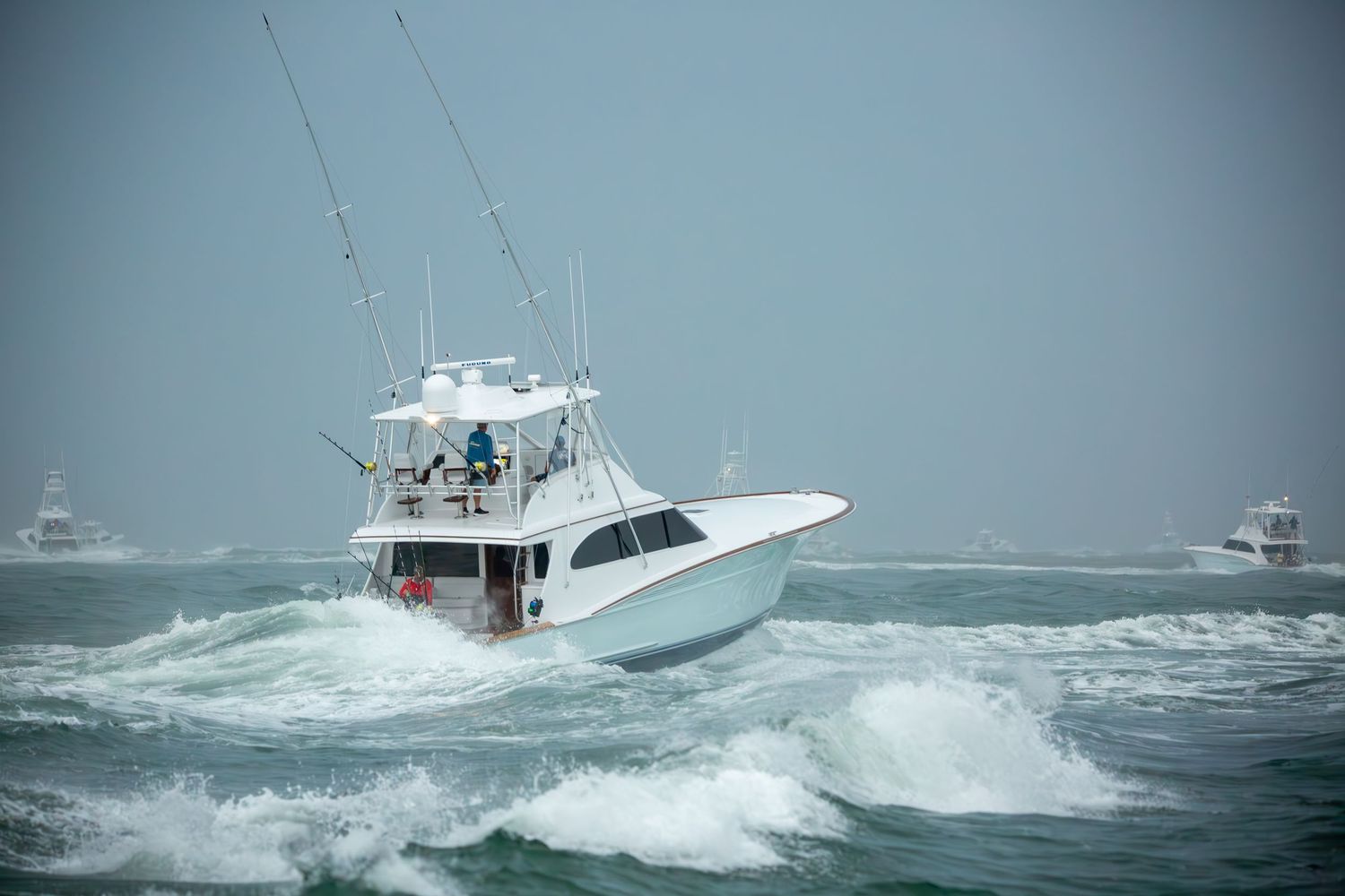 Luxury sport fishing yacht powers through heavy seas with white spray.
