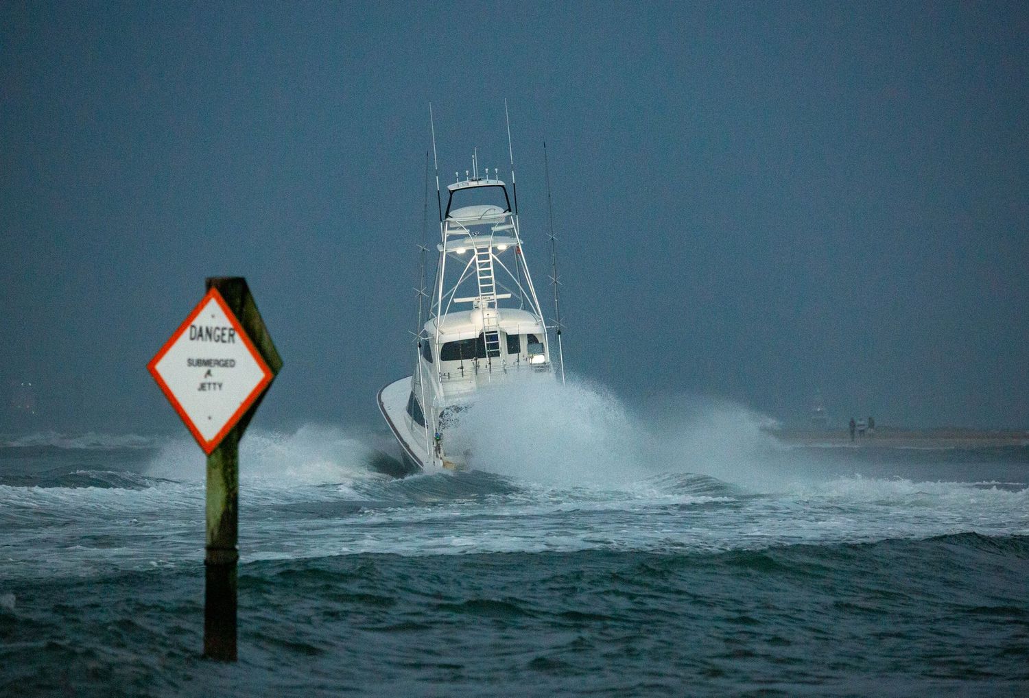 Sportfishing vessels power through choppy seas past navigation markers in overcast weather.