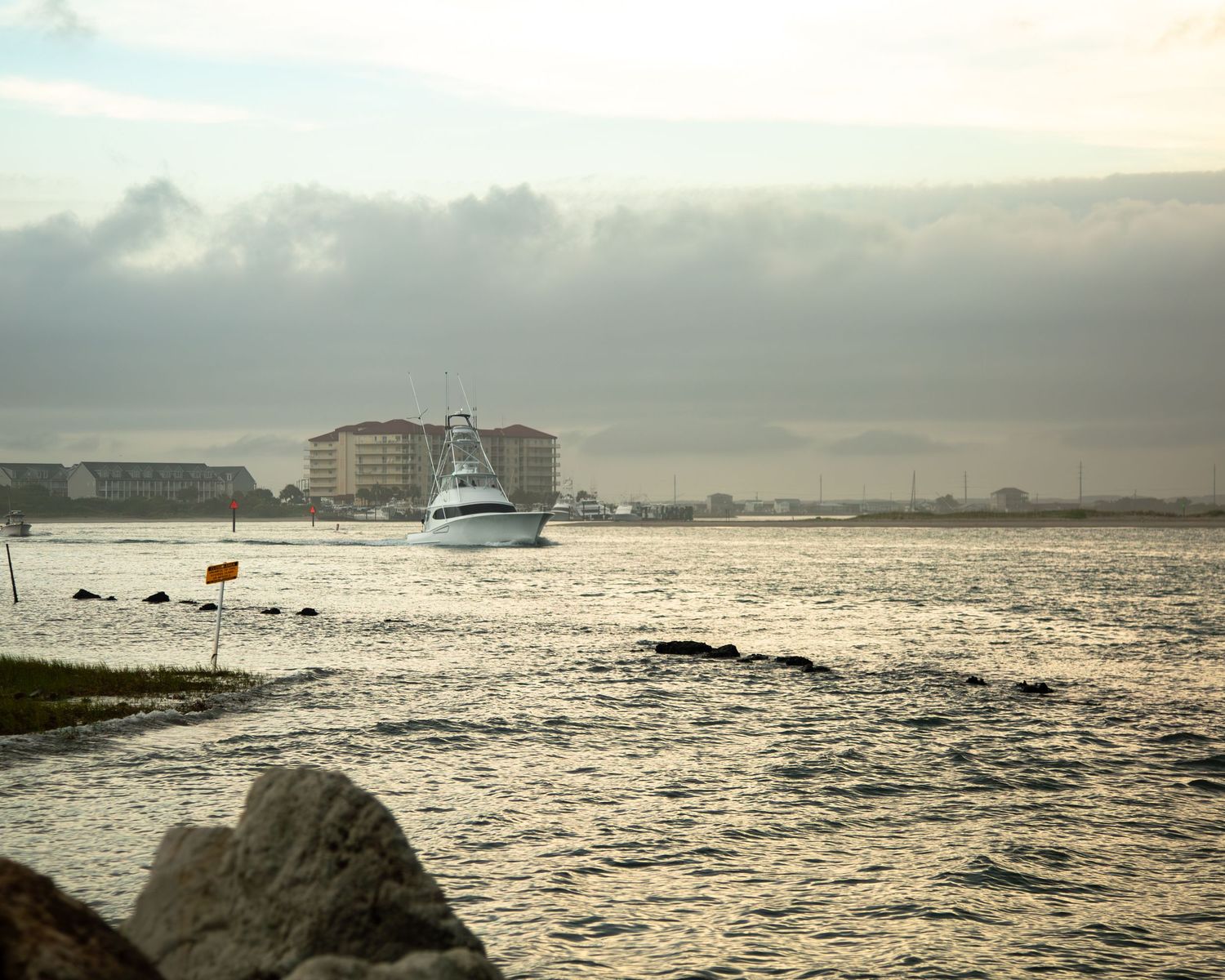 Boats in harbor at sunset with seabirds perched on rocks in the foreground.