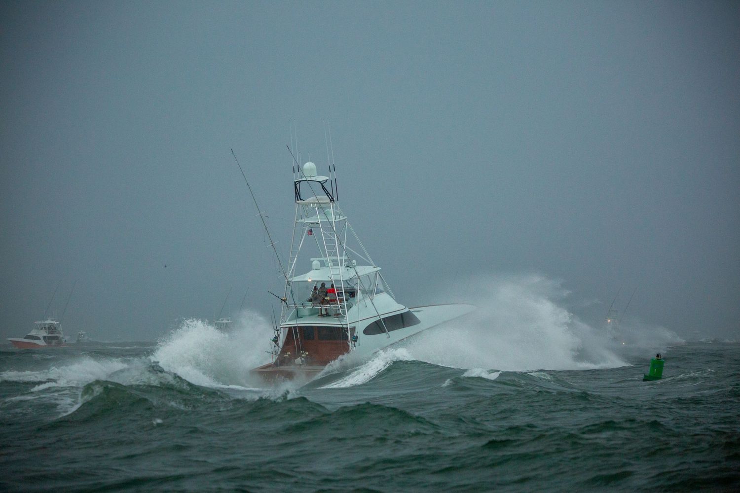 Sport fishing vessel crashes through large waves during stormy weather at sea.