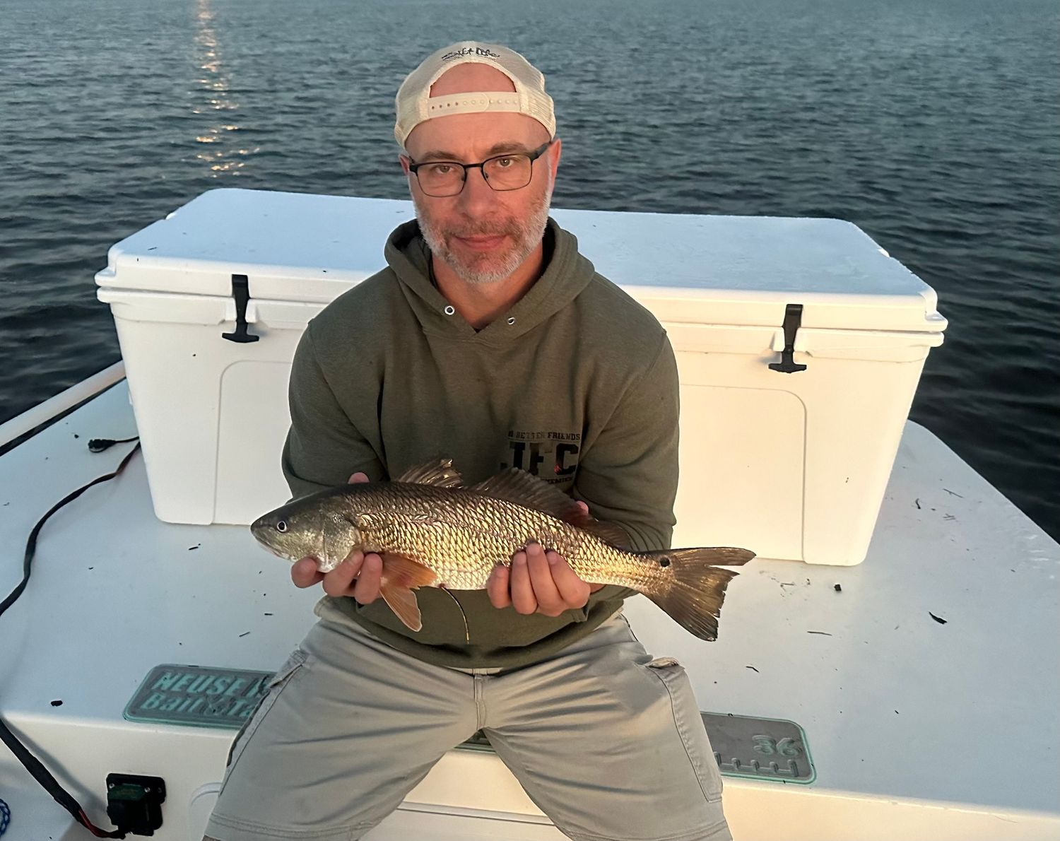 Fishing success showcased with a redfish catch next to white coolers on boat deck.