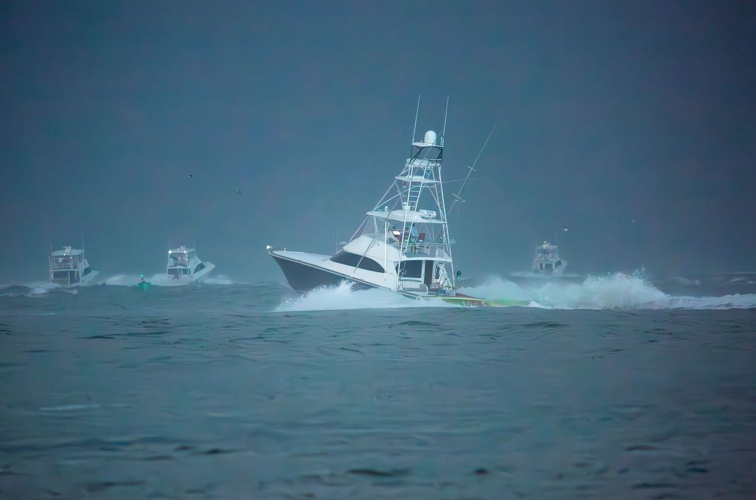 White sport fishing vessel powers through choppy waters with waves crashing at its bow.