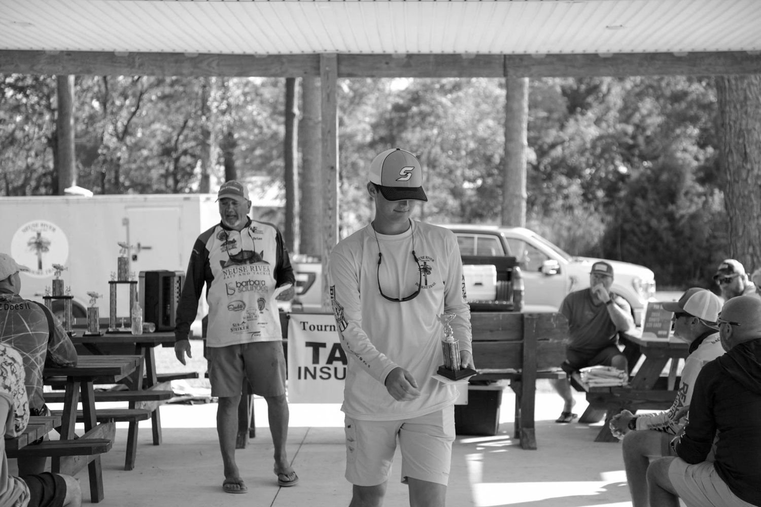 Black and white photo of casual gathering under covered outdoor area.