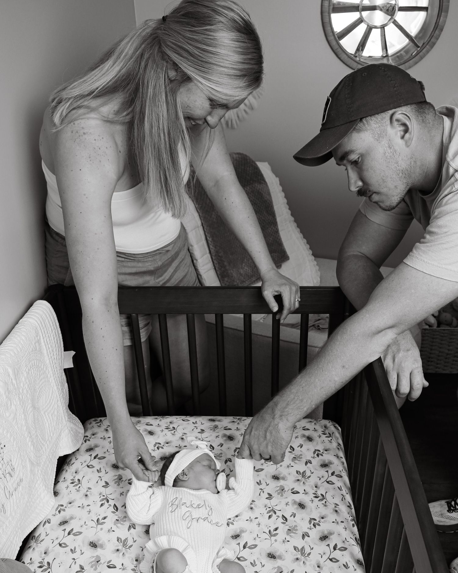 People sign a guest book or document while gathered around a wooden table with decorative clocks on the wall behind them.