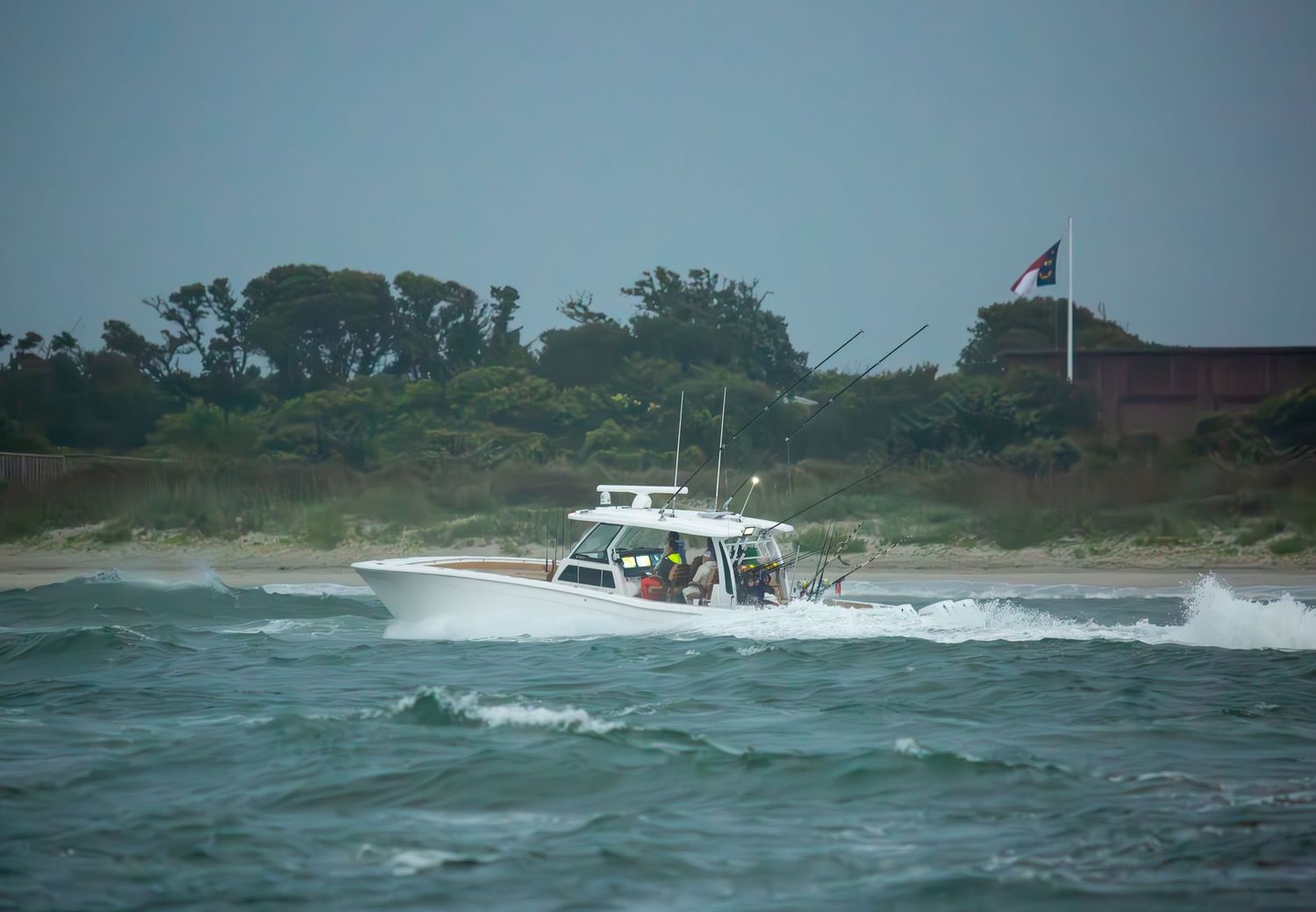 Sport fishing vessels navigate along coastal waters with rough seas near the shoreline.