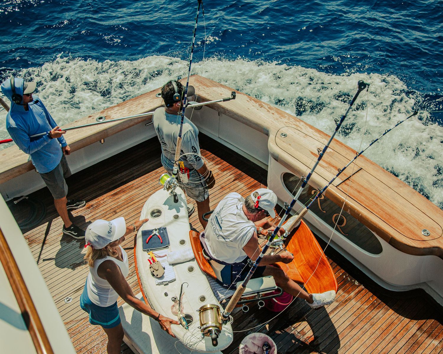 Aerial view of fishing crew on yacht deck with multiple deep sea fishing rods and reels.
