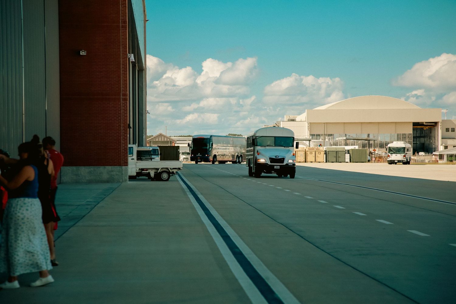 Panoramic view of industrial buildings and warehouses under bright blue sky with scattered clouds.