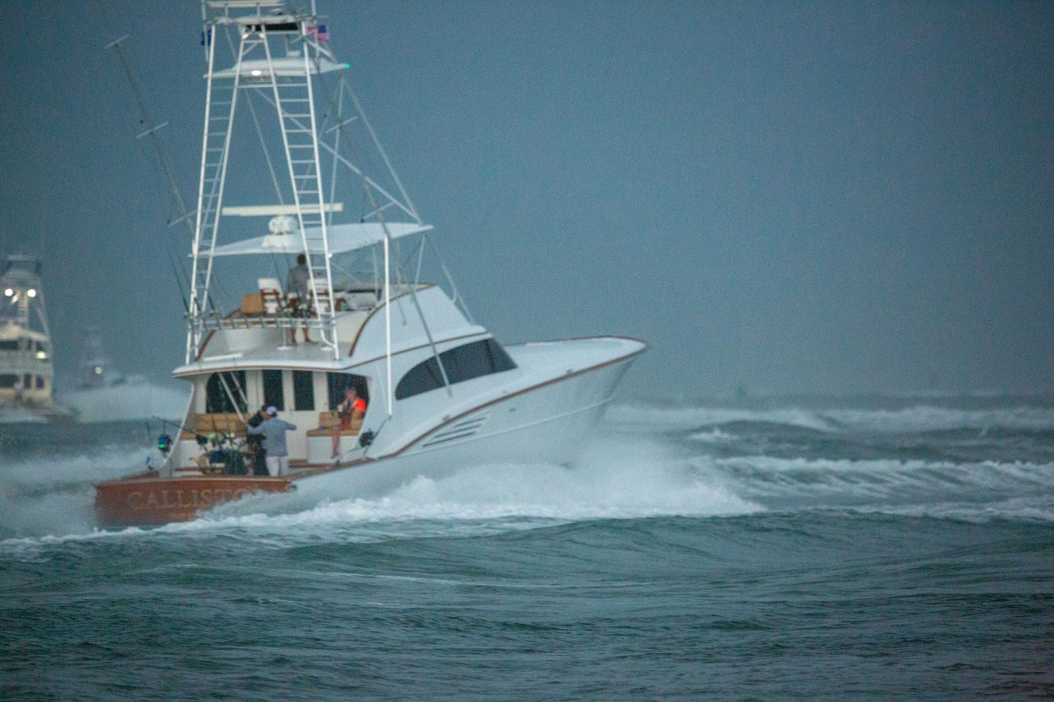 White sport fishing boats navigate through rough ocean waves and spray.