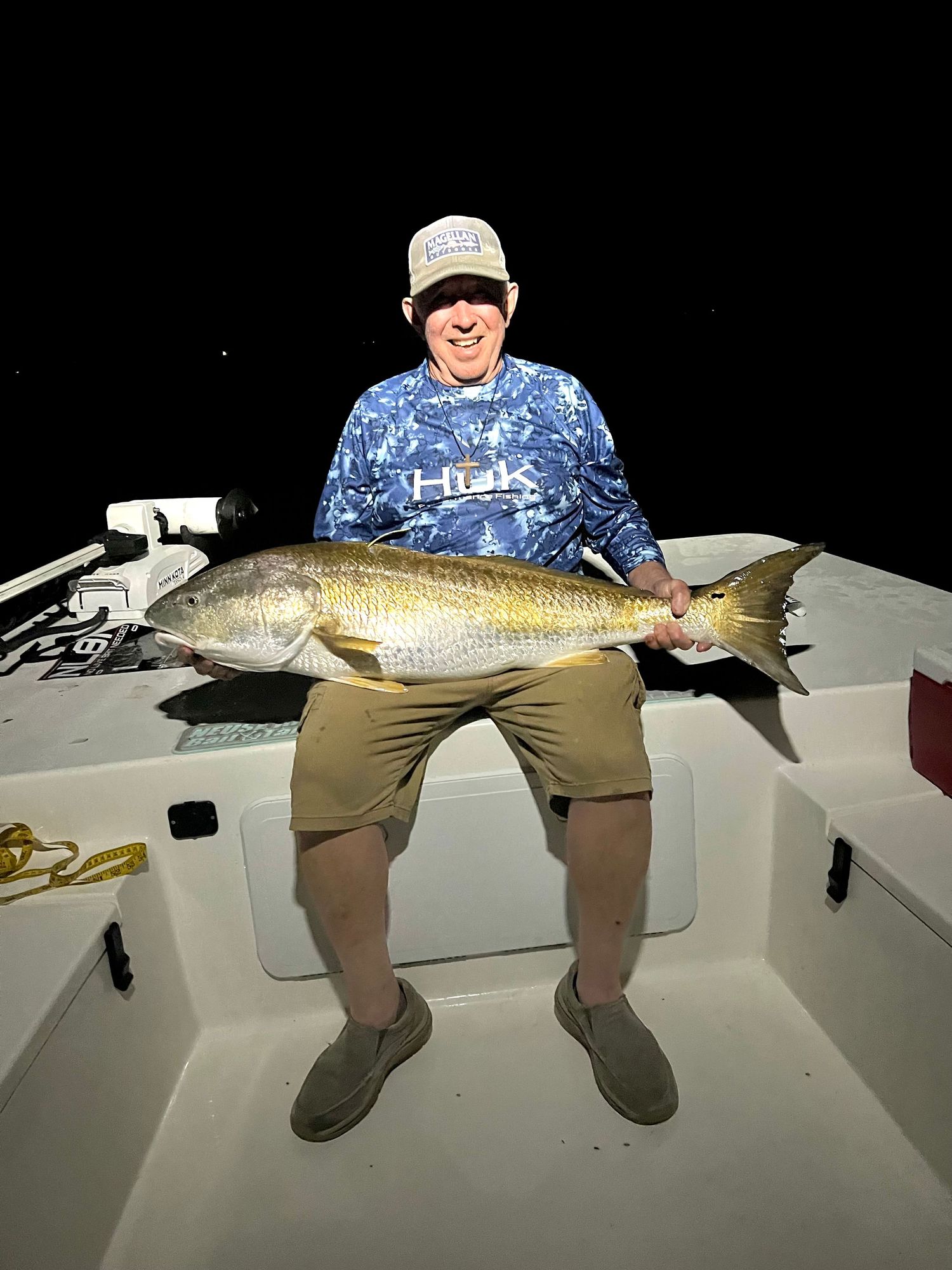 Large redfish caught during nighttime fishing expedition on boat.