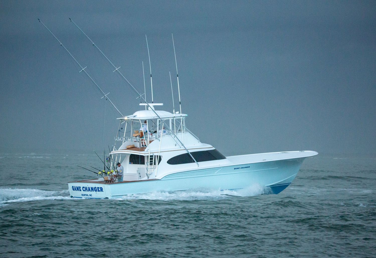Luxury fishing boat powers through heavy seas with water spraying from bow.