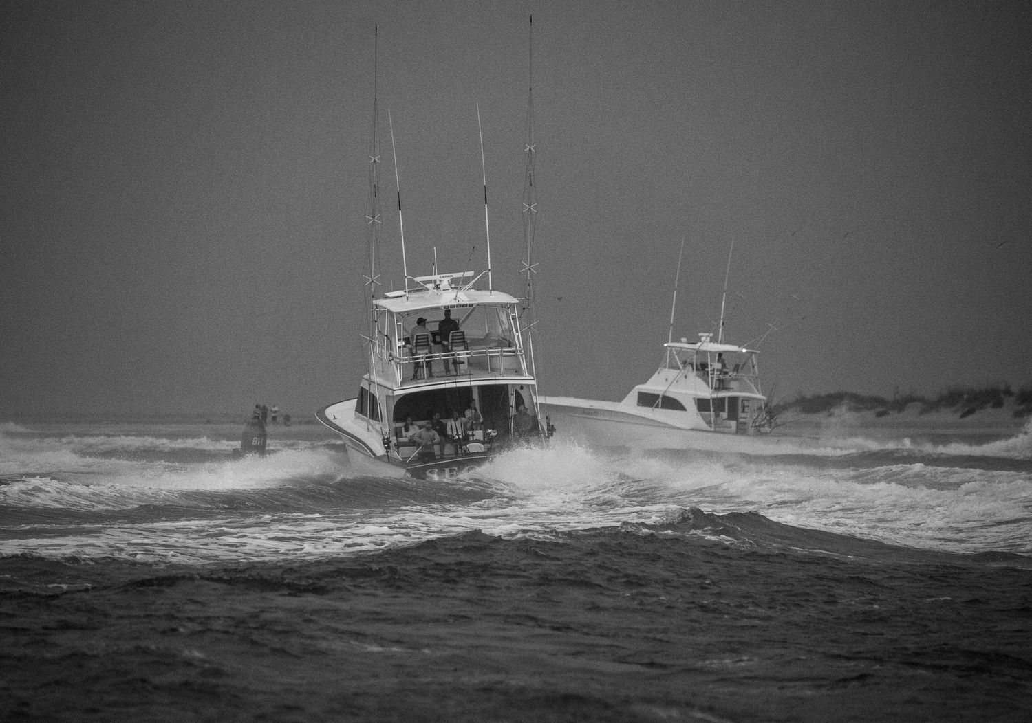 Black and white image of fishing boats battling rough ocean conditions.