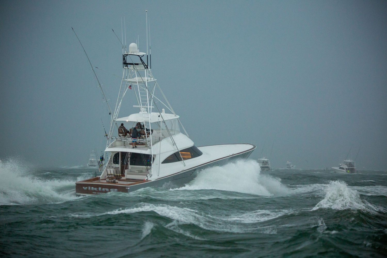 White fishing boats traverse through choppy waters during stormy weather near channel markers.
