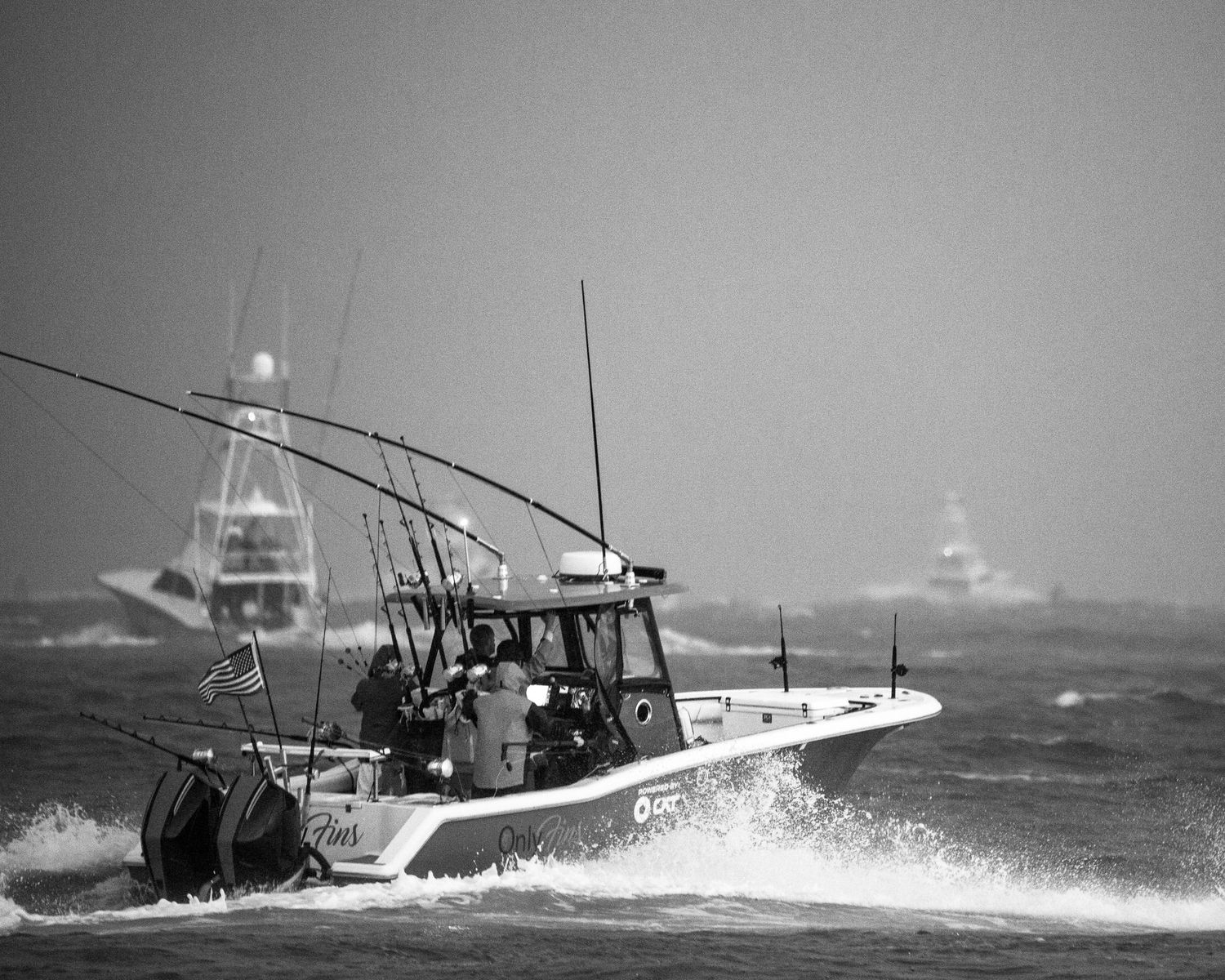Sport fishing boats battling large waves in choppy ocean waters.