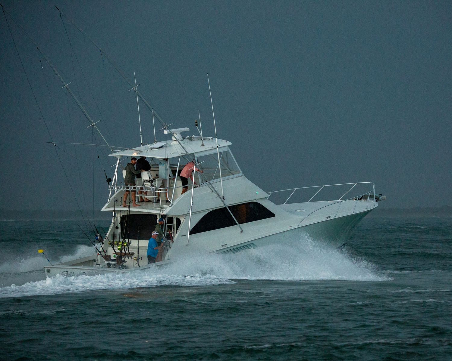 Deep sea fishing vessels battle through rough ocean swells in dark weather.