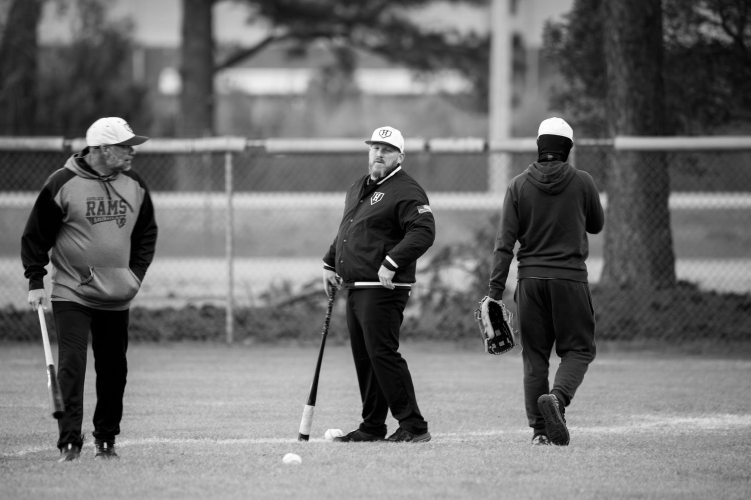 Three people walking on a baseball field in black and white.