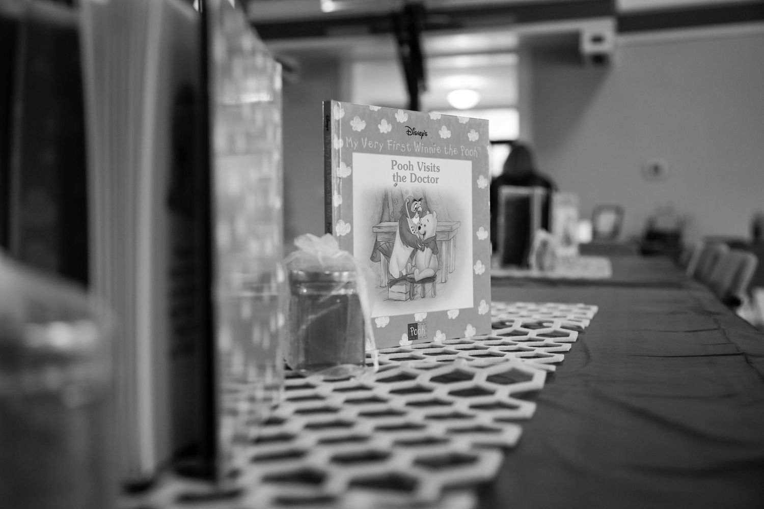 Black and white photo of a Paddington Bear book displayed on a patterned tablecloth at a children's party.