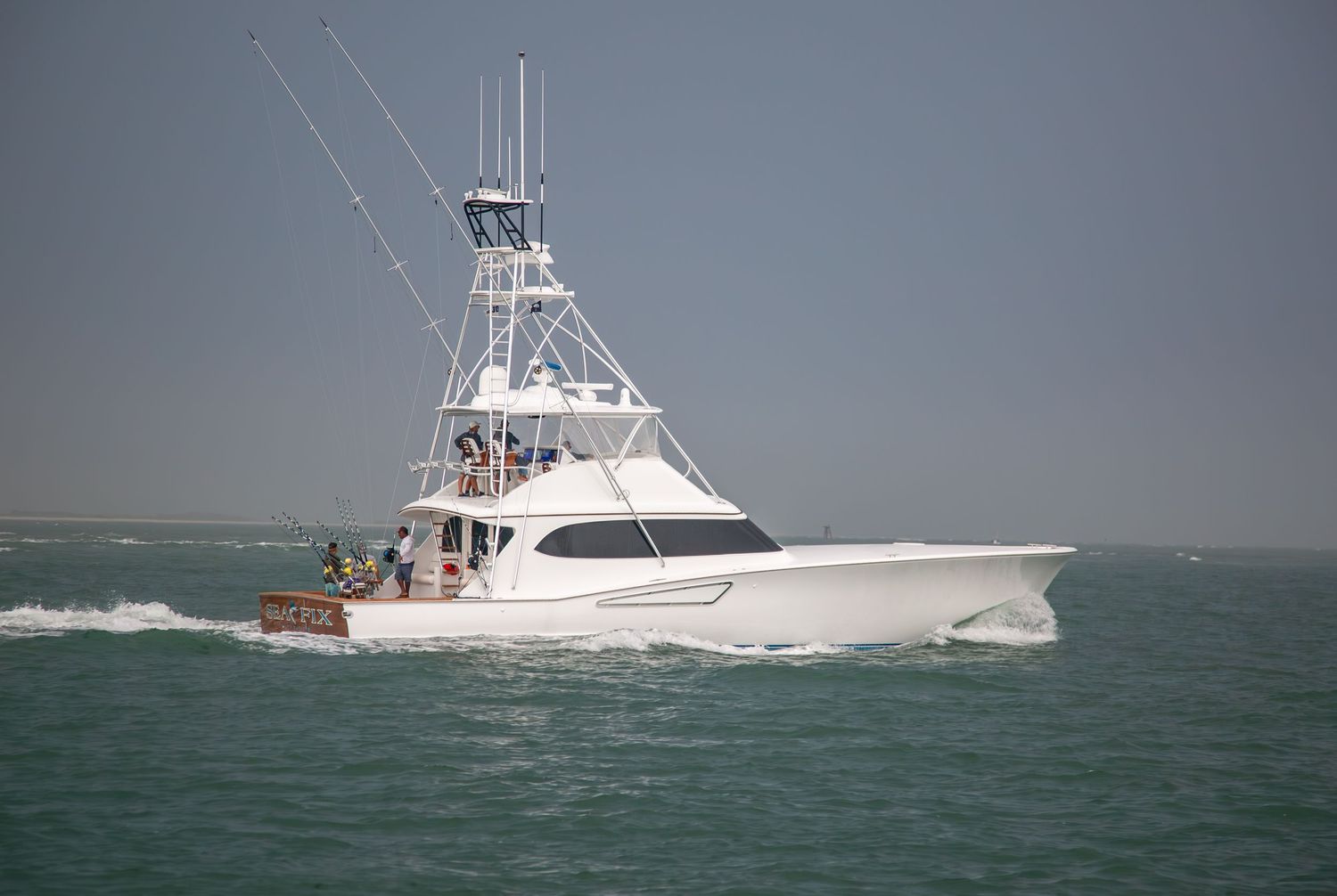 Luxury sportfishing boat cutting through blue ocean waves on a clear day.