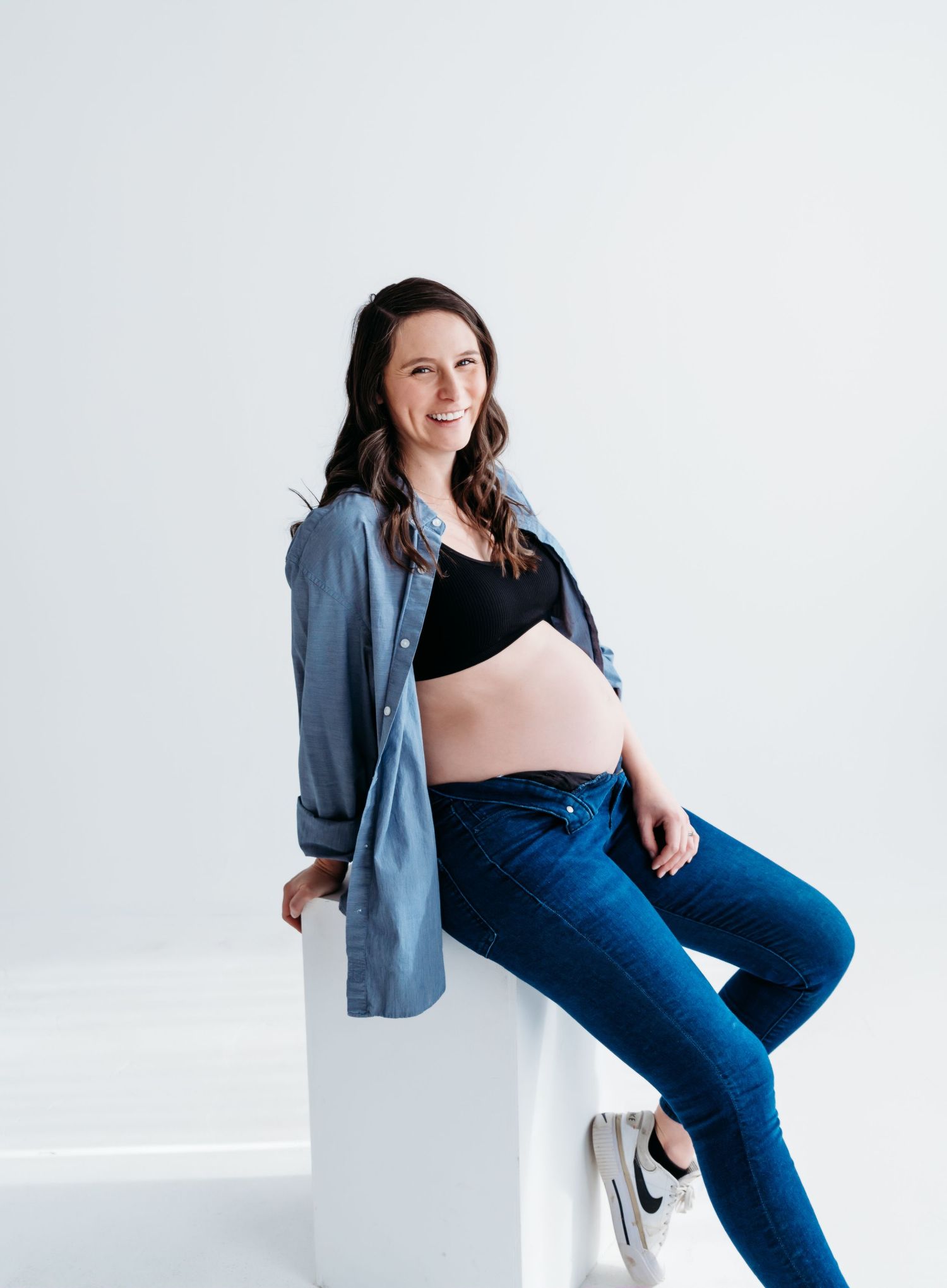 Maternity portrait of an expectant mother in casual denim and button-down shirt.