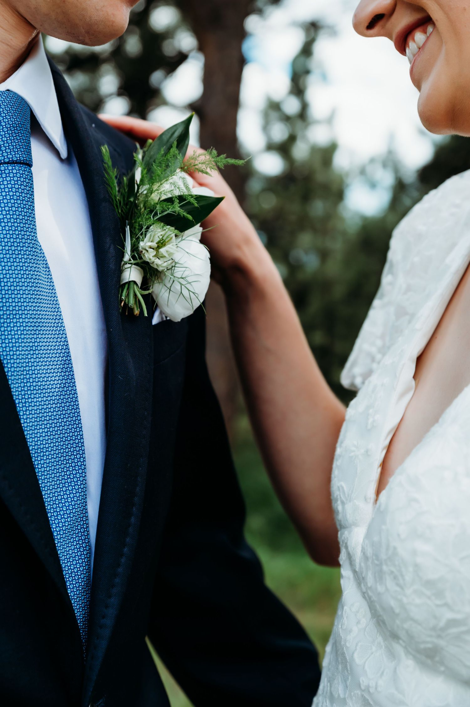 Close-up detail of a blue tie and white boutonniere at a wedding.