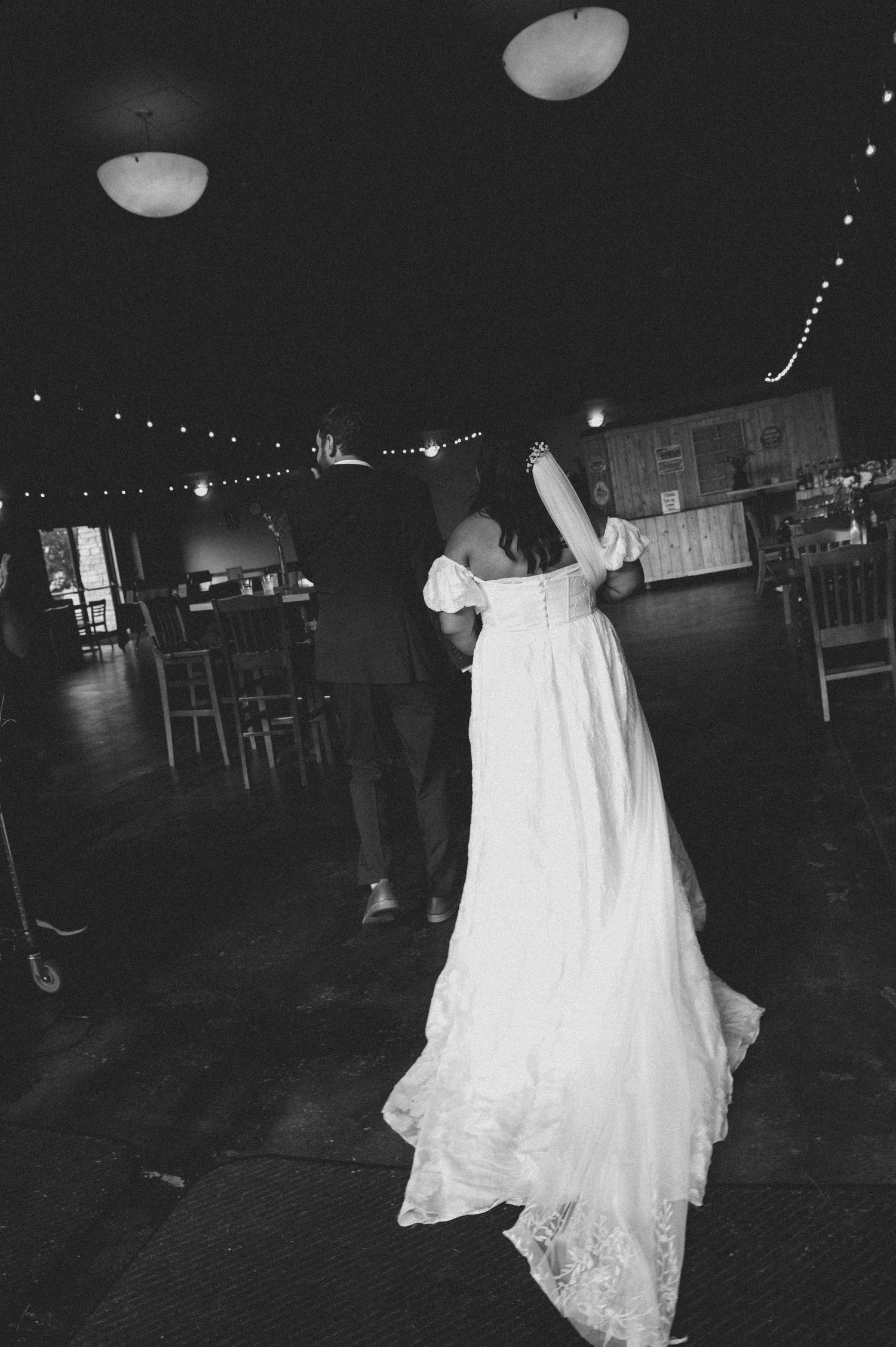 A sequence of black and white photos showing a bride in a flowing white wedding dress dancing in a dimly lit reception hall.