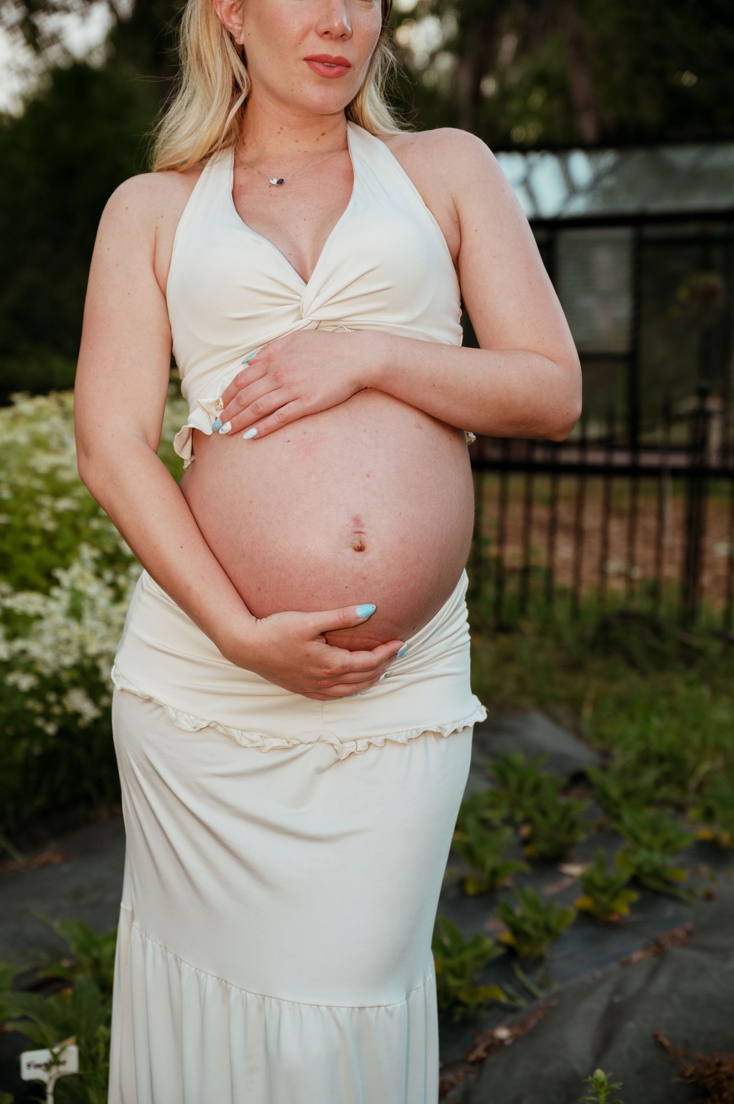A progression of pregnancy photos showing a growing baby bump in a white dress against an outdoor garden setting.