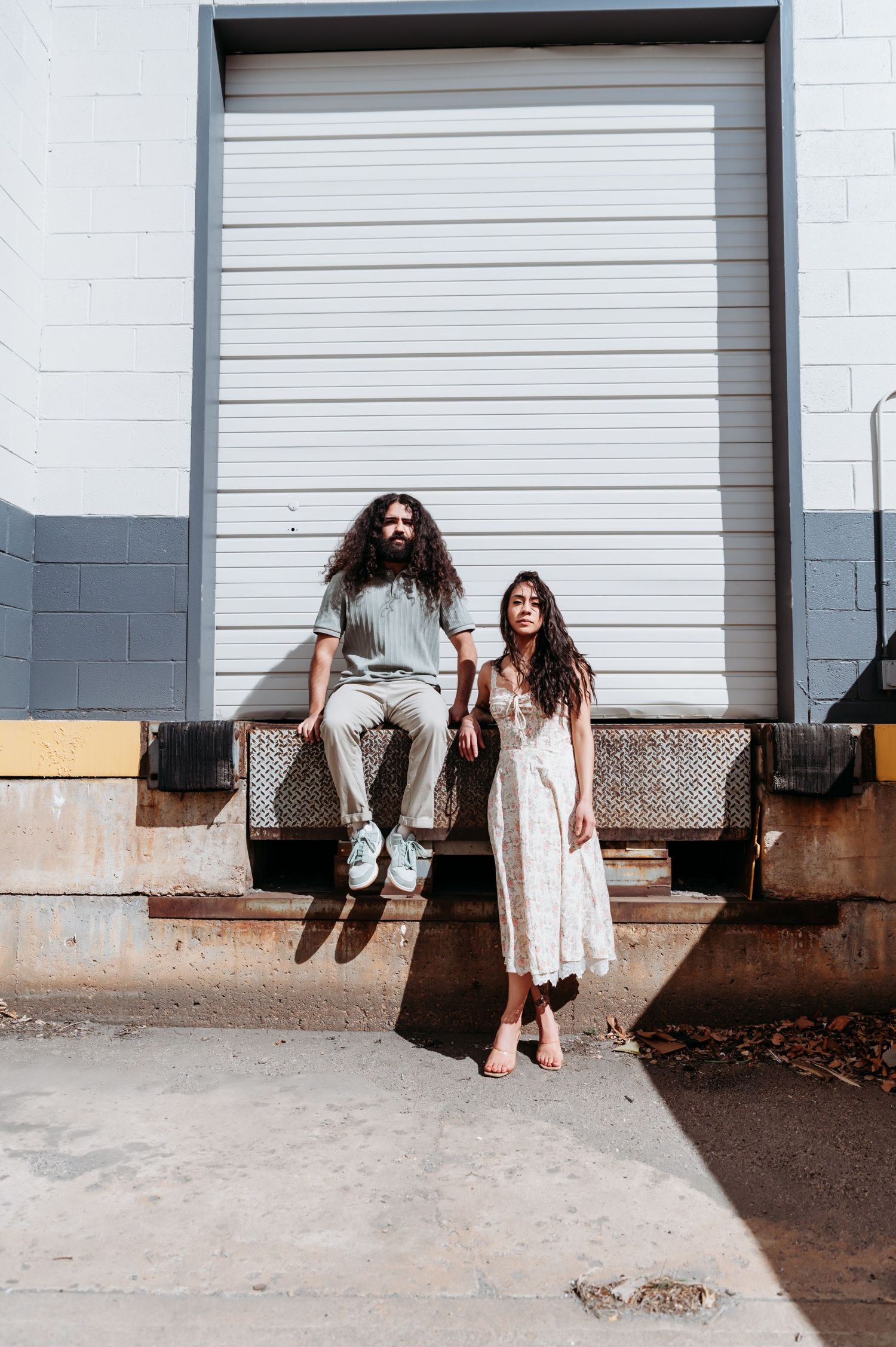 Four sequential photos show a person in white clothing sitting and moving along a concrete ledge against industrial doors.