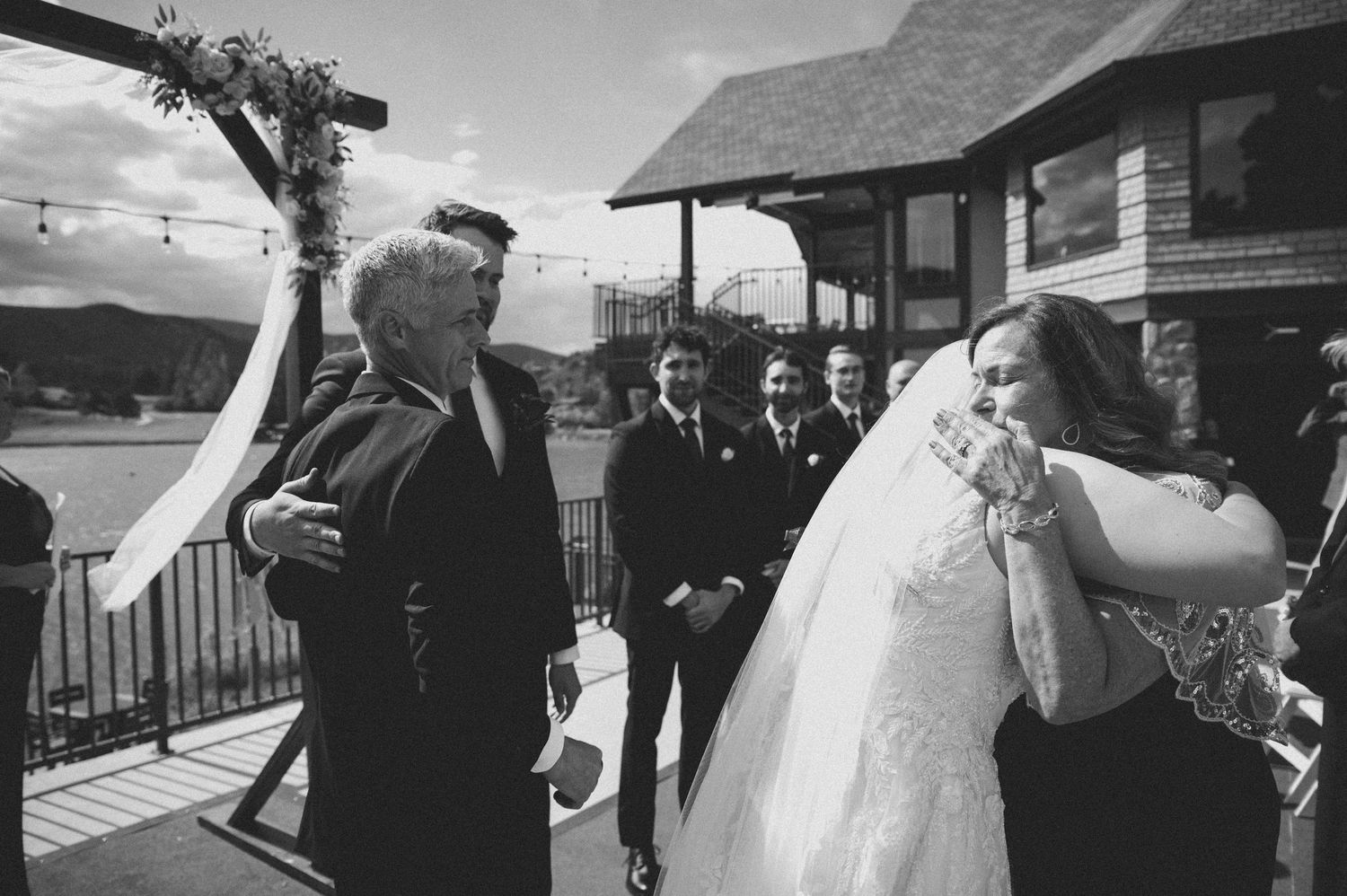 Black and white wedding photos showing romantic moments between newlyweds and guests at an outdoor ceremony.