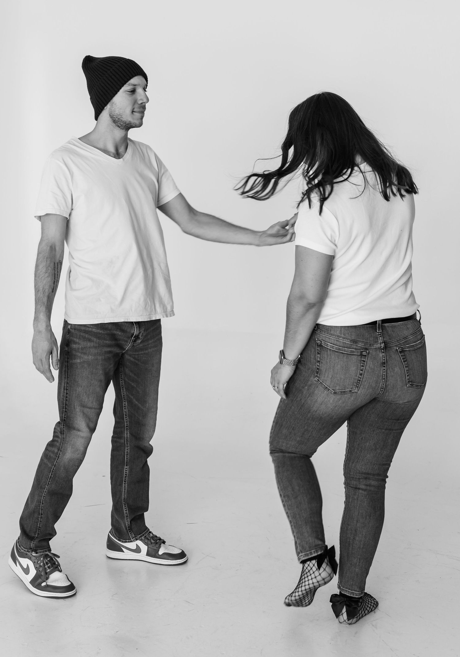 A playful black and white photo of two people in casual wear dancing.