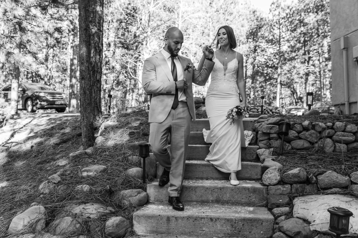 A couple descends stone steps together at their outdoor wedding celebration.
