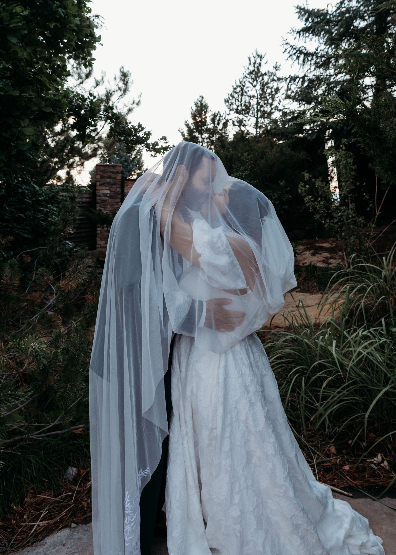 A series of ethereal wedding photos showing a white gown and veil flowing in the breeze against a garden backdrop.