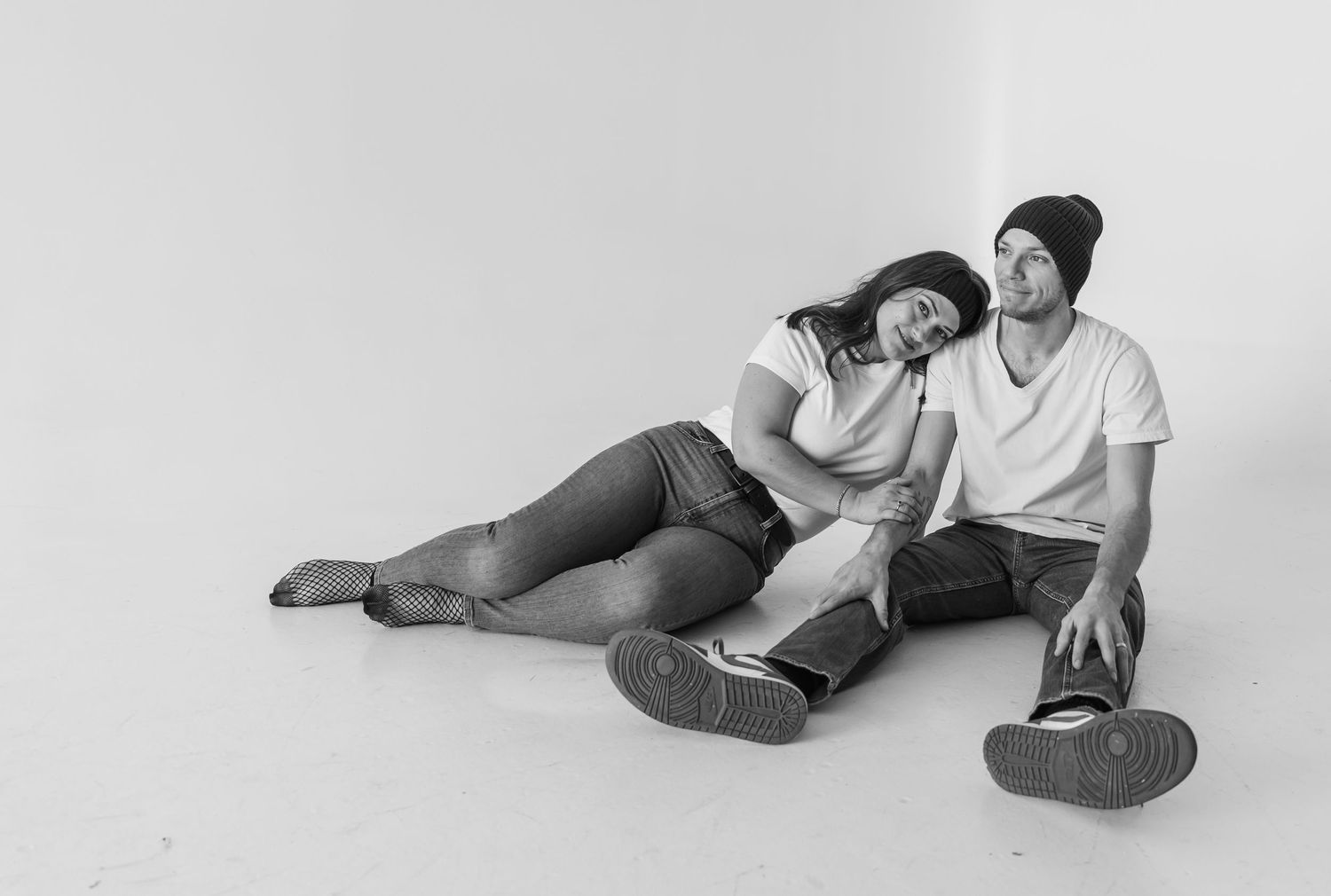 Four black and white portraits show a couple lying together on a floor in casual, intimate poses.