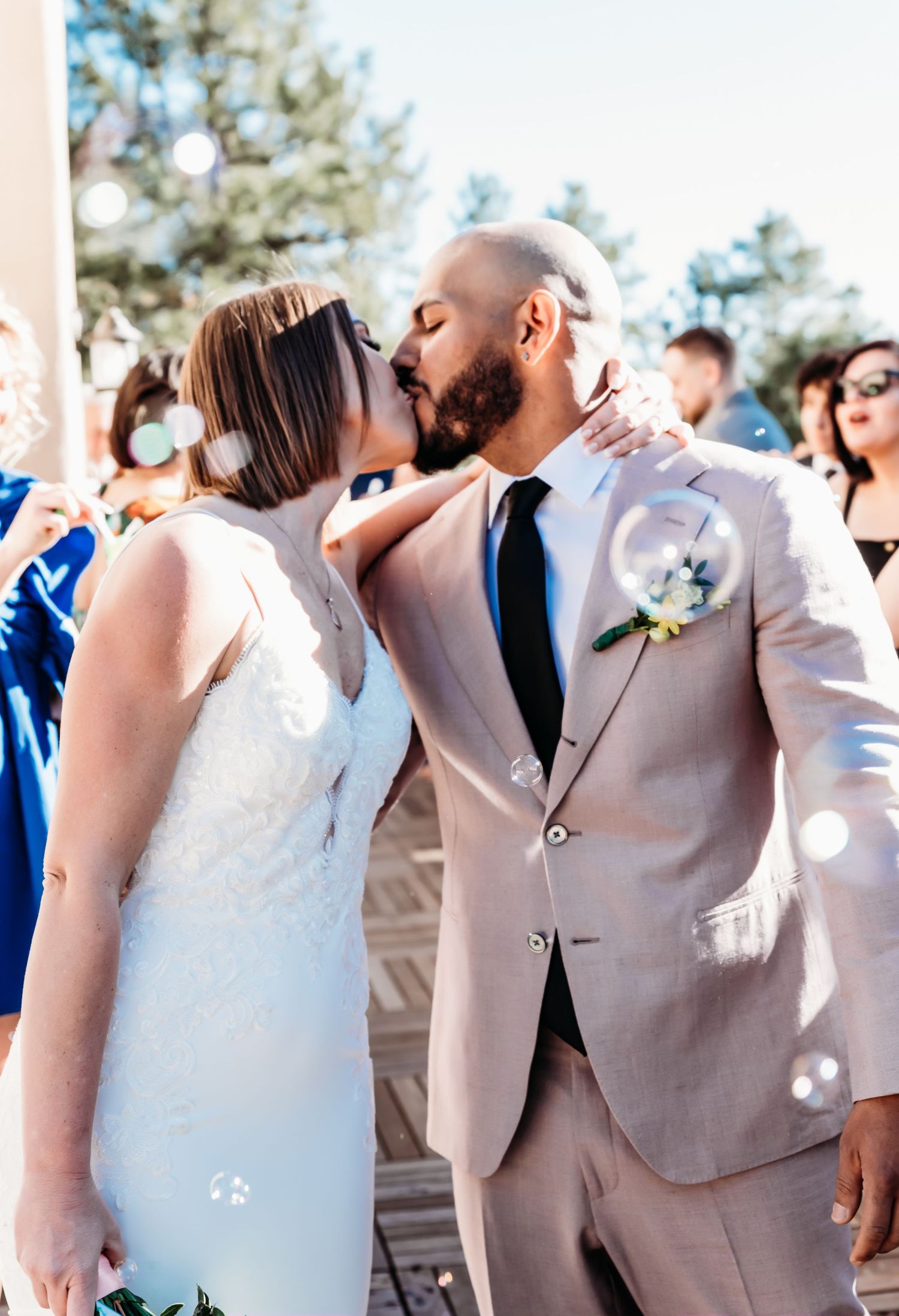 A couple shares their first kiss at an outdoor wedding ceremony.